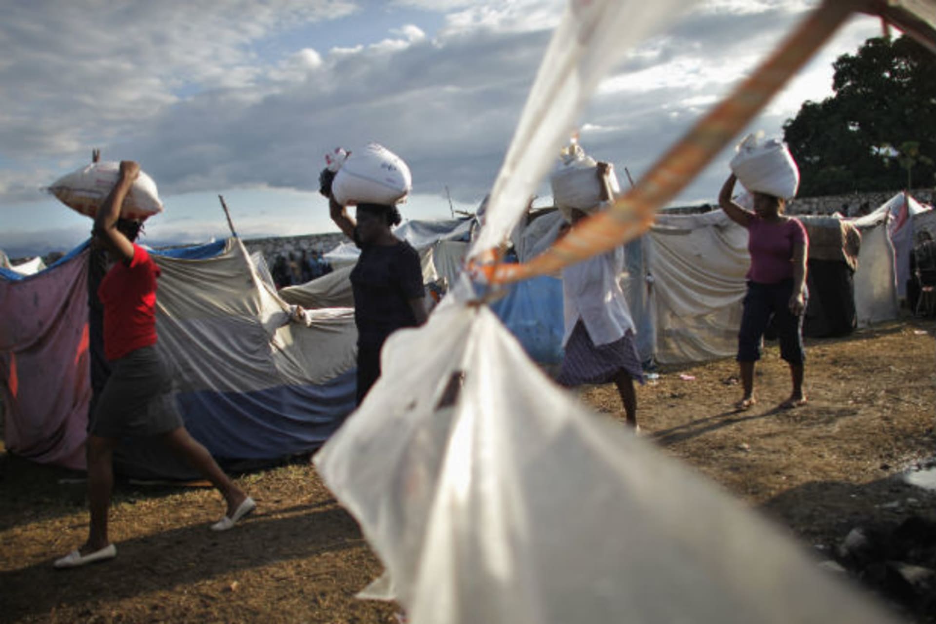 <p>Women carry bags of rice from USAID in Cite Soleil, Port-au-Prince February 18, 2010 (Carlos Barria/Courtesy Reuters).</p>
