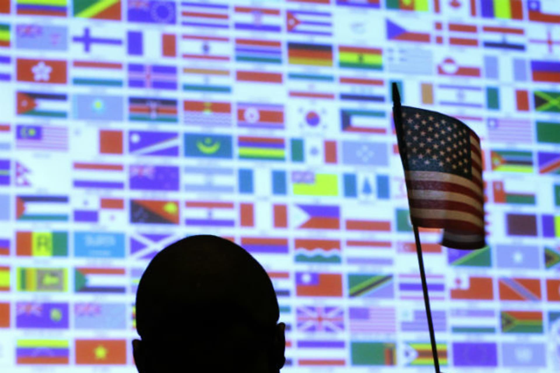 <p>A new U.S. citizen waves a U.S. national flag in front of a display of flags of the more than 40 nations represented by the more than 90 immigrants becoming U.S. citizens during a naturalization ceremony at Boston College in Chestnut Hill, Massachusetts</p>
