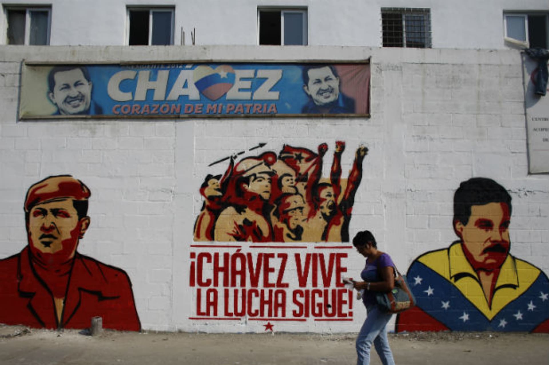 <p>A woman walks past a mural depicting Venezuela’s acting President and presidential candidate Nicolas Maduro (R) and Venezuela’s late President Hugo Chavez in Caracas April 12, 2013 (Tomas Bravo/Courtesy Reuters).</p>
