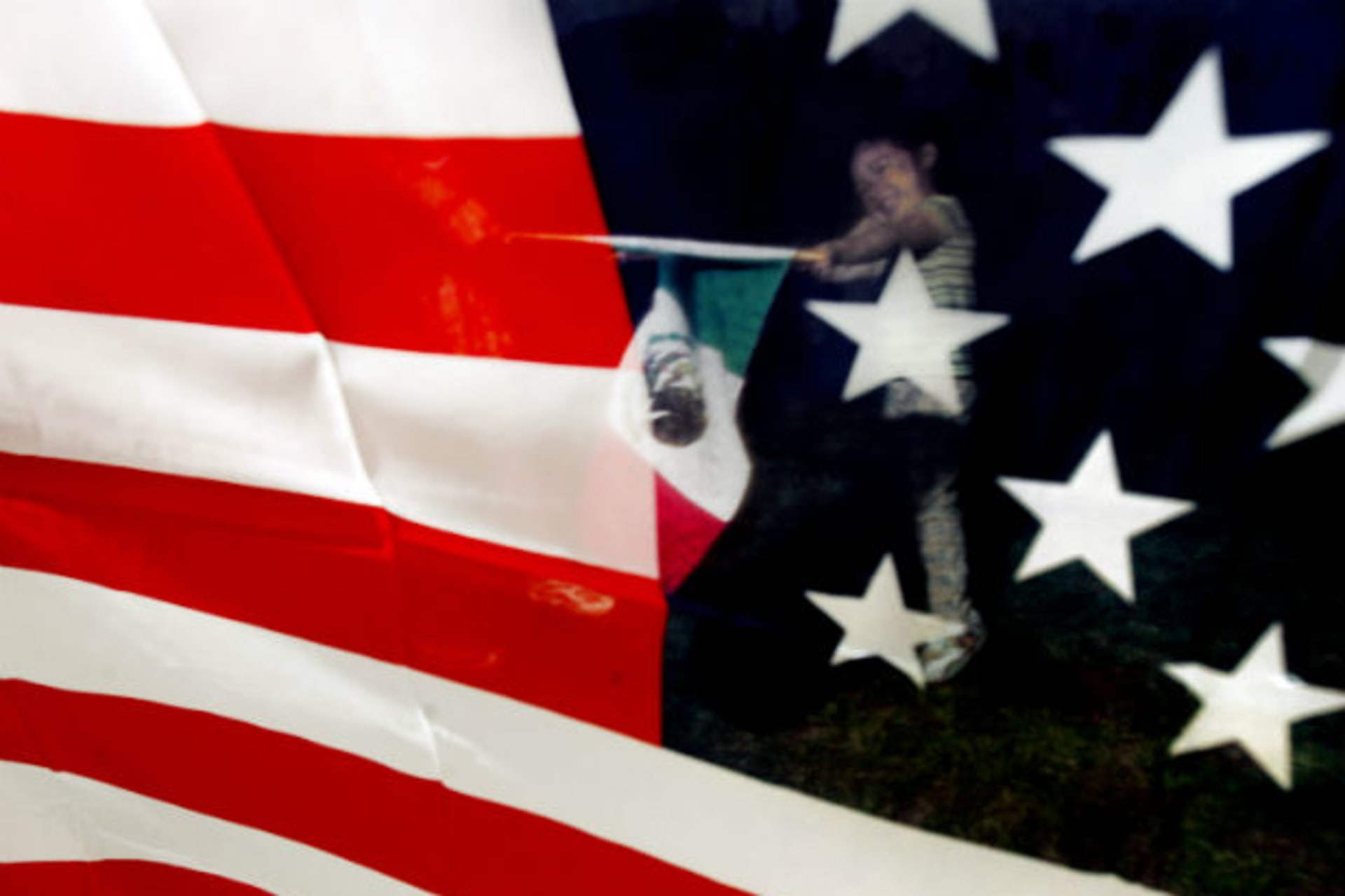 <p>Yaritza Hernandez is seen through an American flag as she waves a Mexican flag during a rally in support of immigration rights in Washington, May 17, 2006 (Jim Young/Courtesy Reuters).</p>
