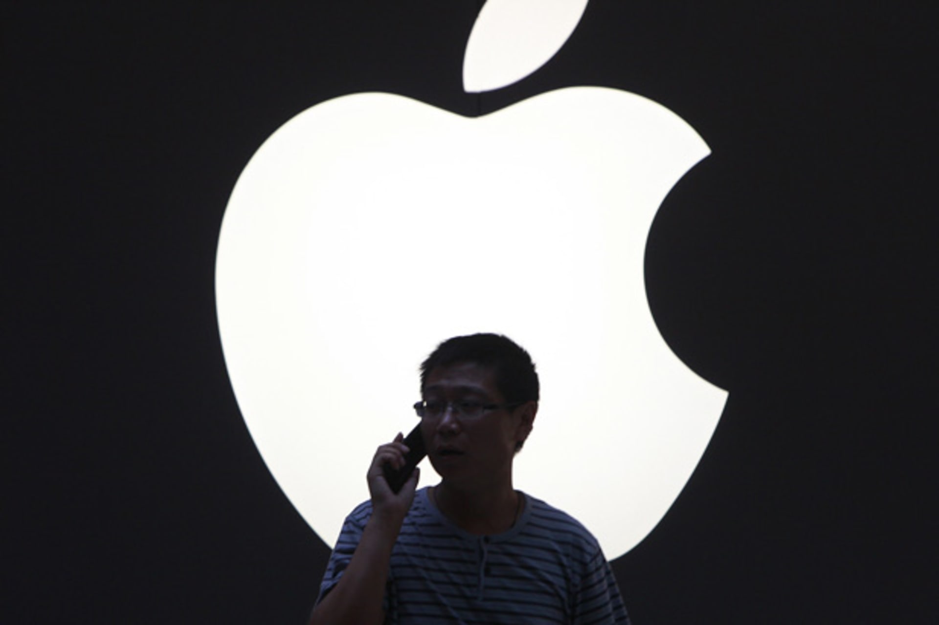 <p>A man talks on a mobile phone in front of an Apple logo outside an Apple store in downtown Shanghai on September 3, 2012 (Aly Song/Courtesy Reuters).</p>
