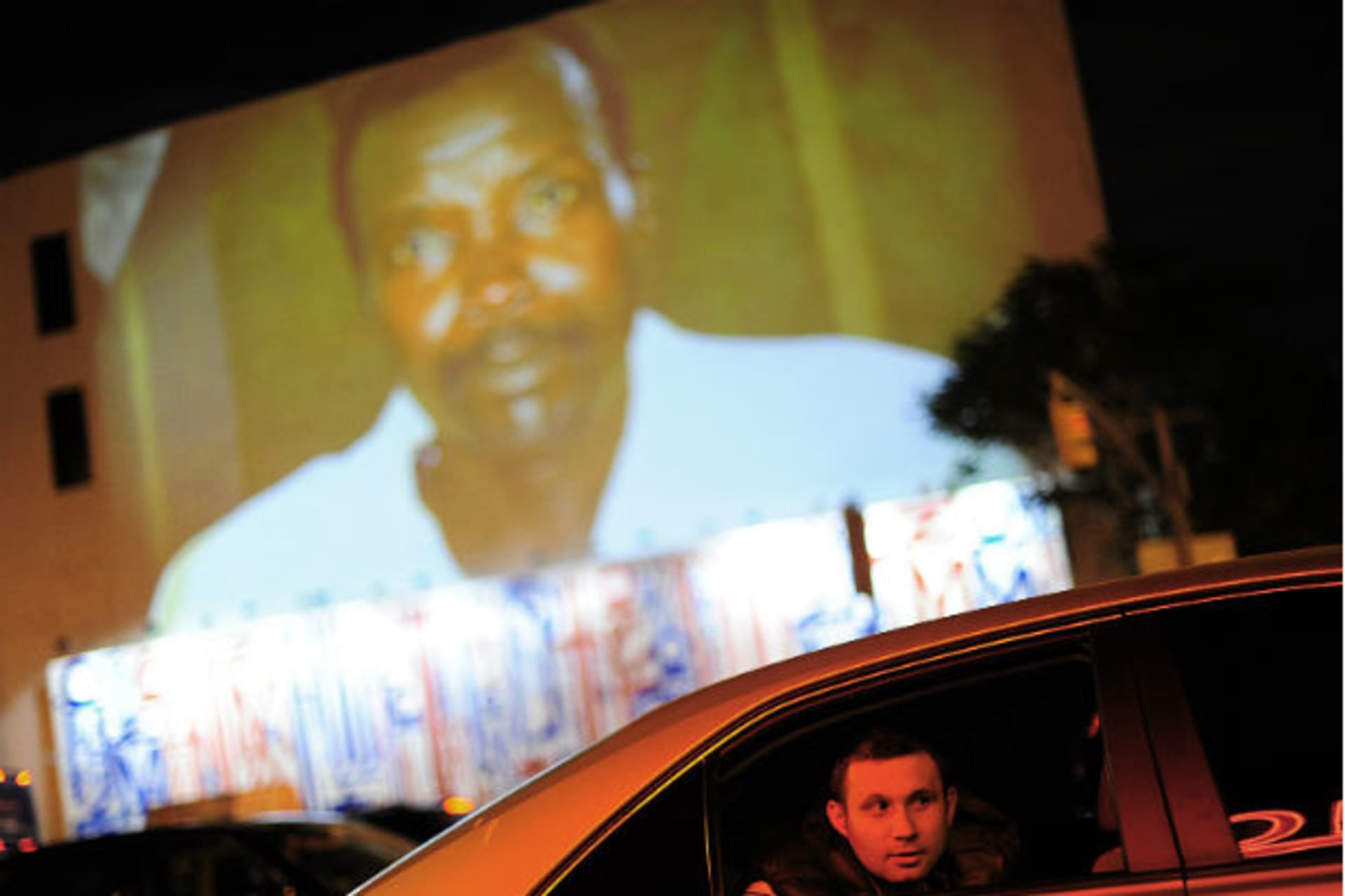 <p>A man looks out of the window of a car which drives under a projection that is part of the non-profit organization Invisible Children’s “Kony 2012” viral video campaign, in New York on April 20, 2012 (Keith Bedford/Courtesy Reuters).</p>

