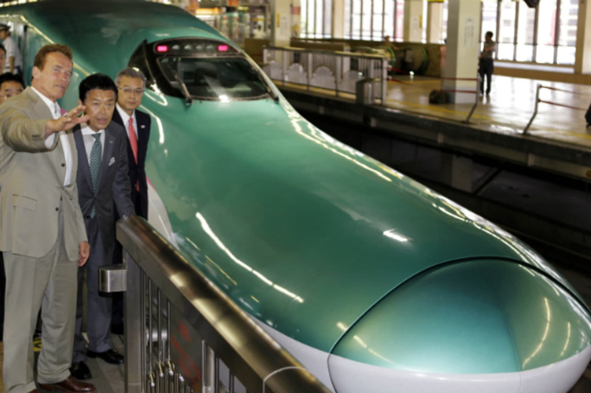 <p>East Japan Railway’s Vice President and Arnold Schwarzenegger stand near a bullet train during a tour of Japan’s high speed train operations in September 2010 (Pool/Courtesy Reuters).</p>

