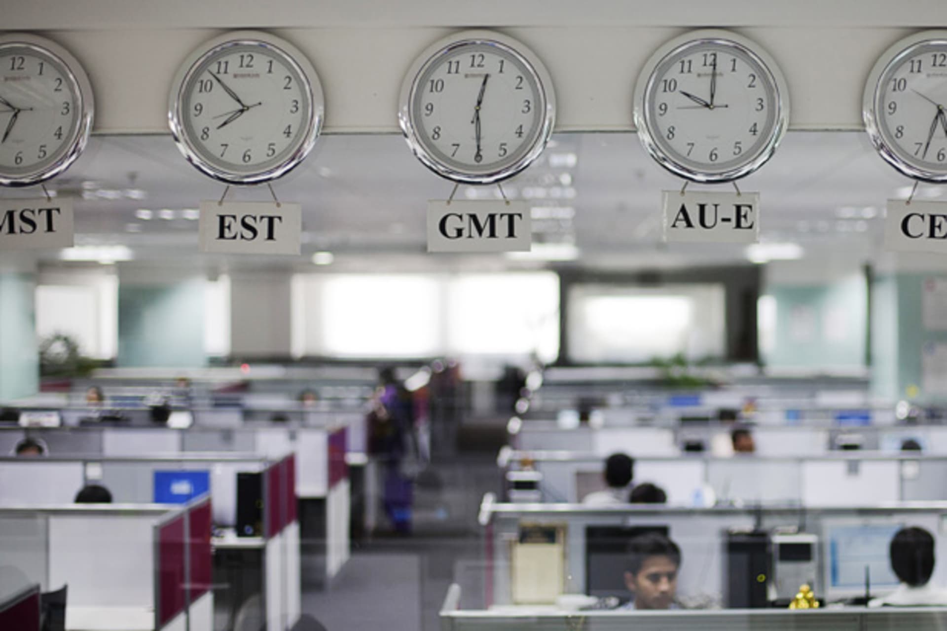 <p>Workers are pictured beneath clocks displaying time zones at an outsourcing center in Bangalore (Vivek Prakash/Courtesy Reuters).</p>
