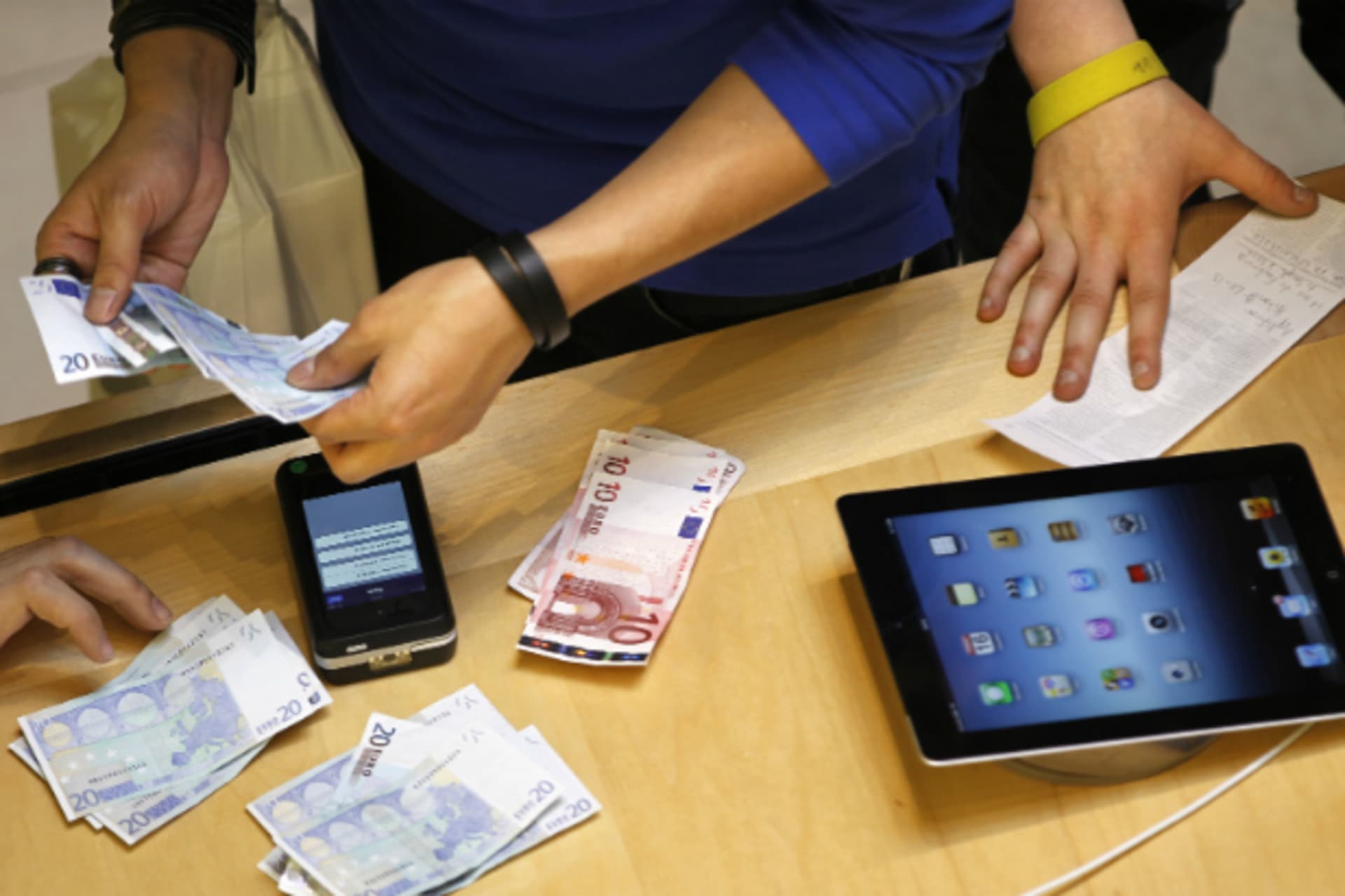 <p>A cashier counts euro banknotes as a customer purchases an Apple iPad in Paris on March 16, 2012 (Charles Platiau/Courtesy Reuters).</p>
