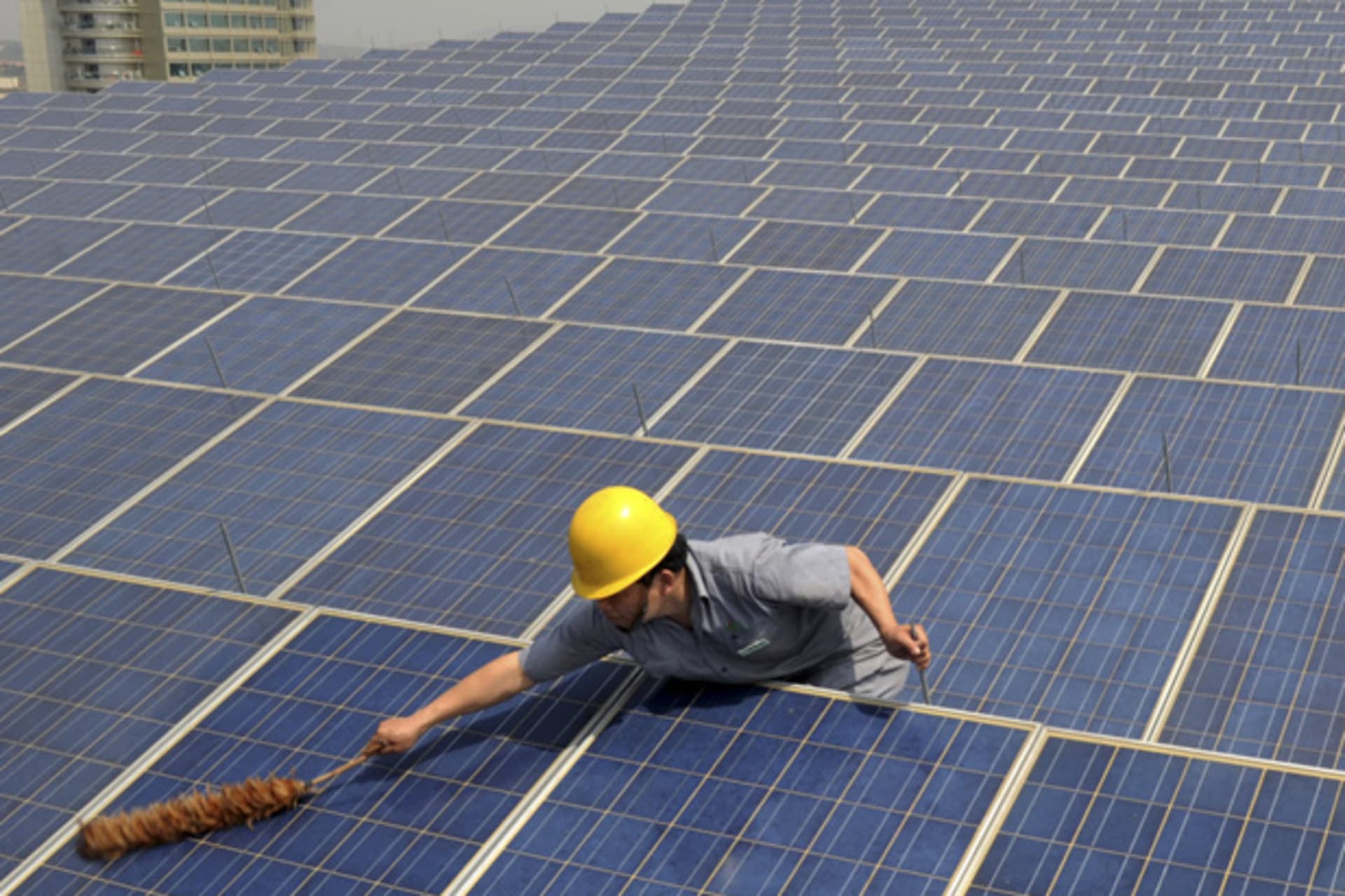 <p>A worker cleans solar panels on a rooftop in Zhejiang Province, China (Stringer/Courtesy Reuters).</p>

