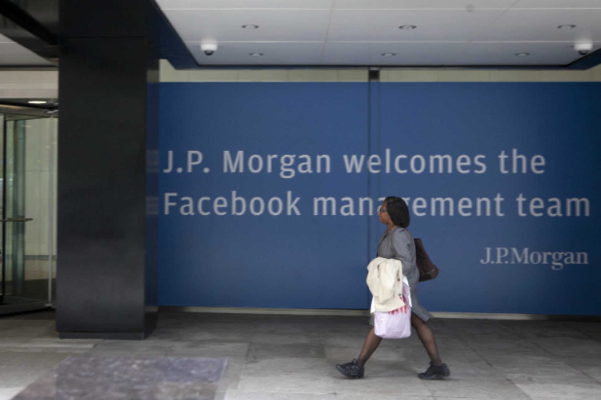 <p>A woman walking near a J.P. Morgan sign welcoming Facebook’s management team in preparation of its IPO. (Lee Celano/Courtesy Reuters)</p>
