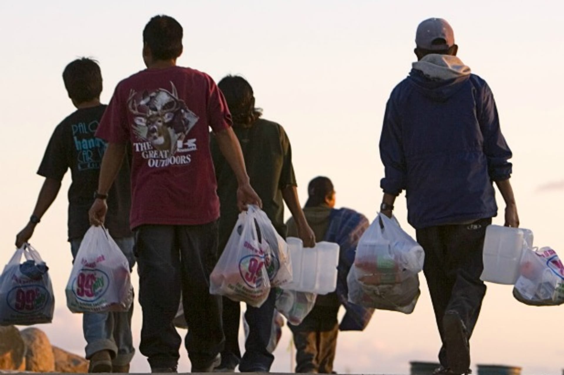 <p>Migrant farm workers walk back to their camp with food and other supplies in San Diego</p>
