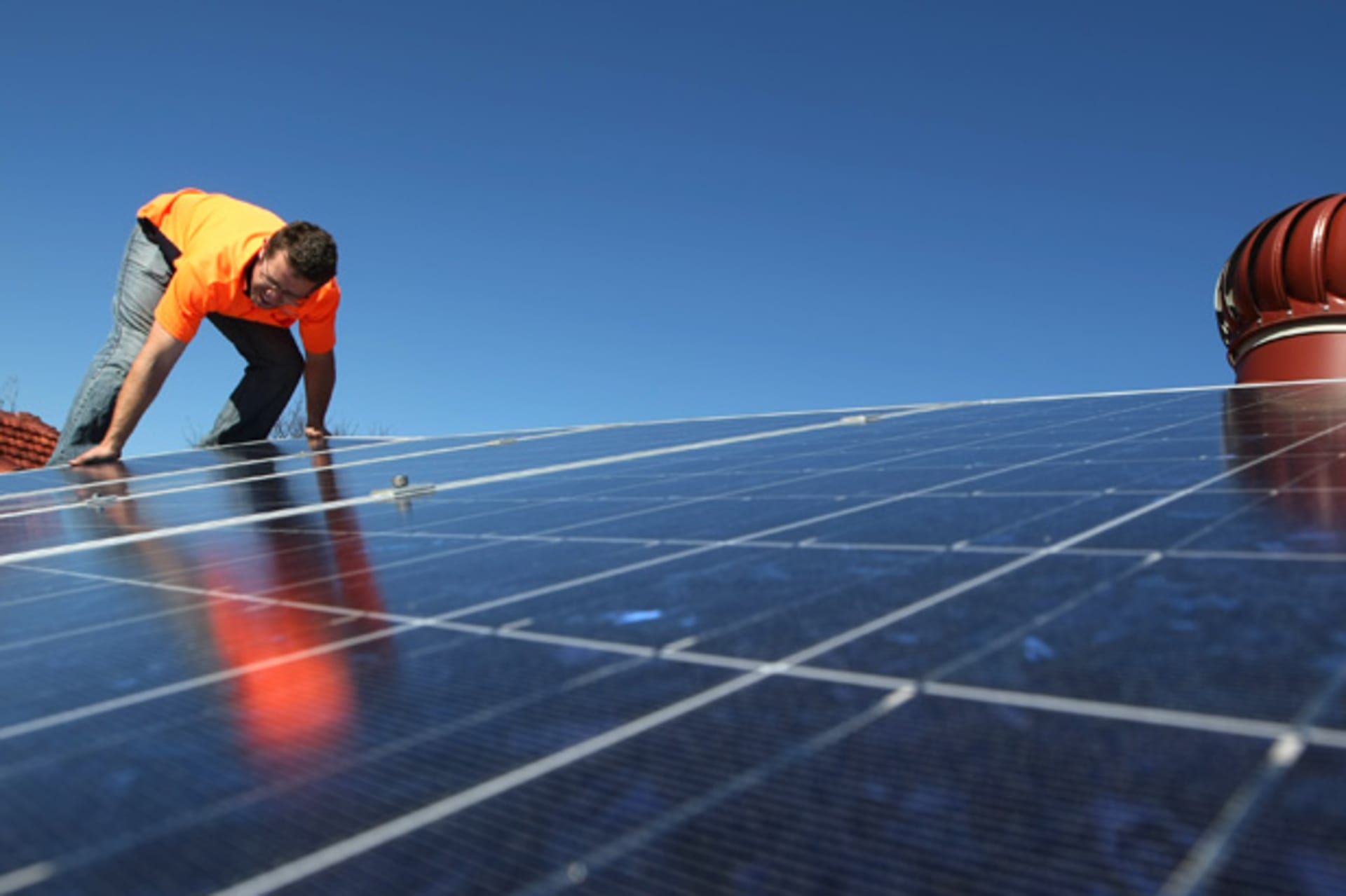 <p>A solar system installer adjusts new solar panels on the roof of a house (Tim Wimborne/Courtesy Reuters).</p>

