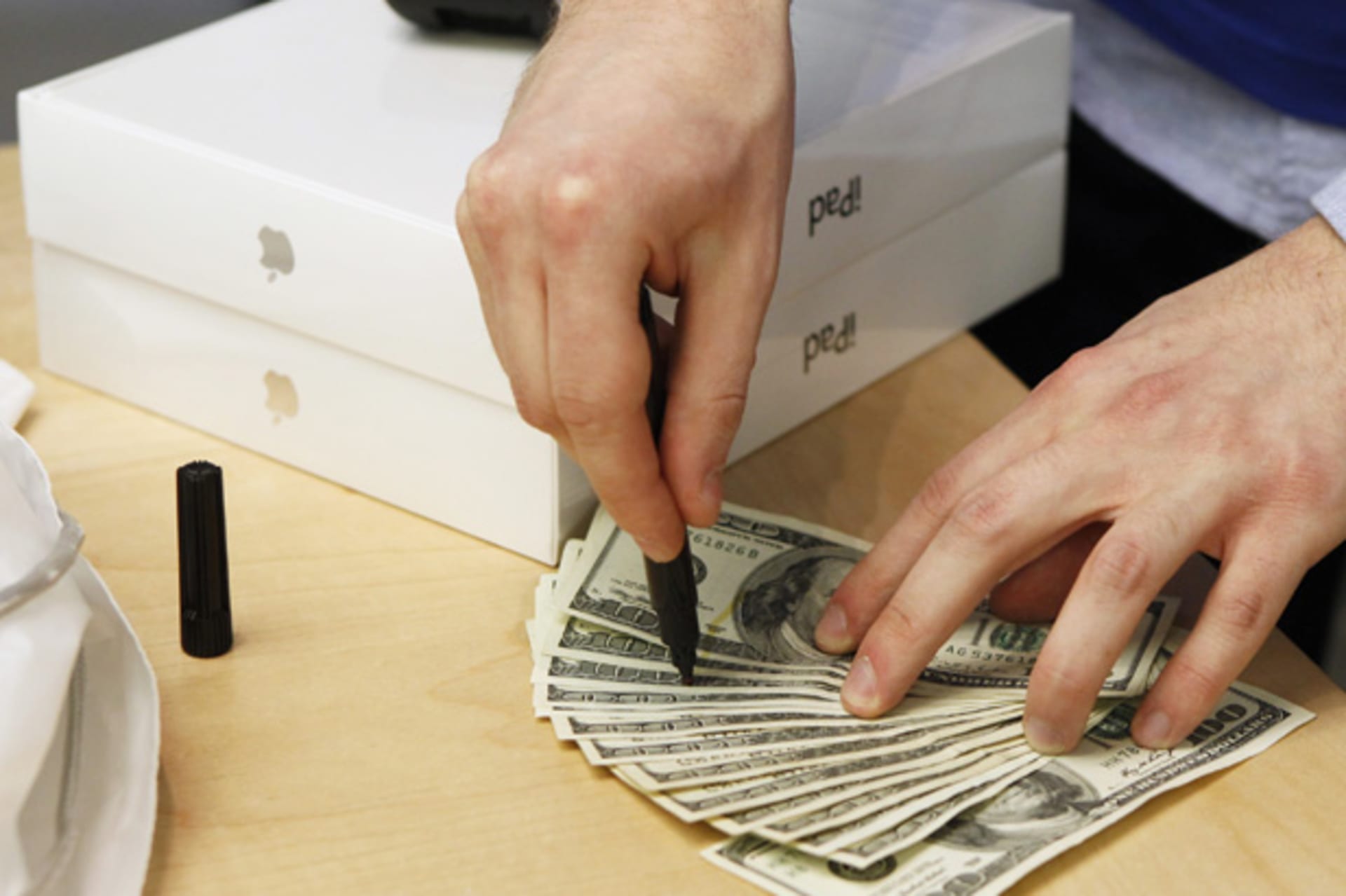 <p>An Apple store employee checks cash for counterfeit bills after a customer purchased a pair of Apple iPad 2 tablets (Lucas Jackson/Courtesy Reuters).</p>
