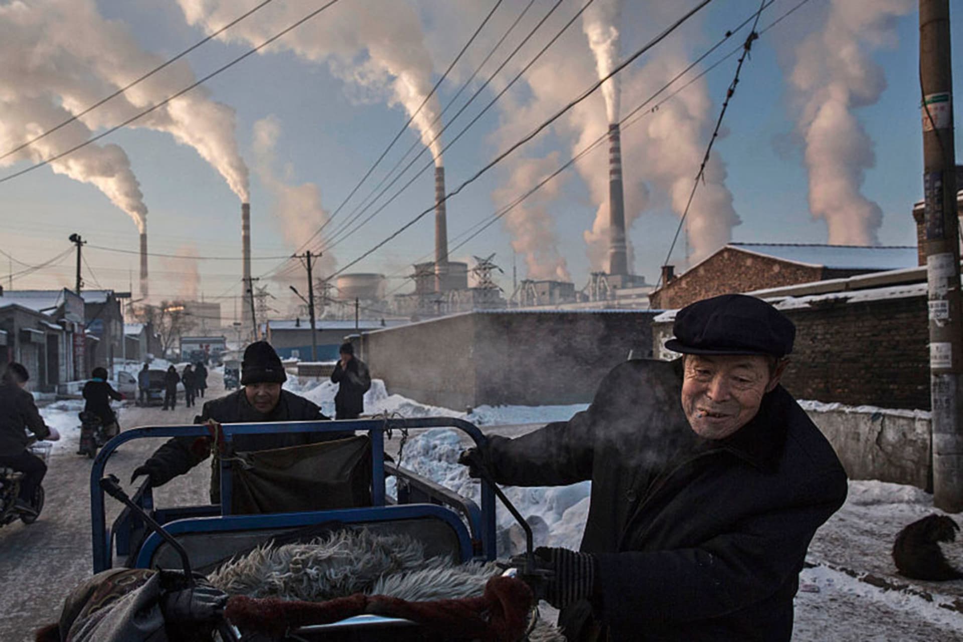 <p>Chinese men pull a tricycle in a neighborhood near to a coal power plant in Shanxi, China.</p>
