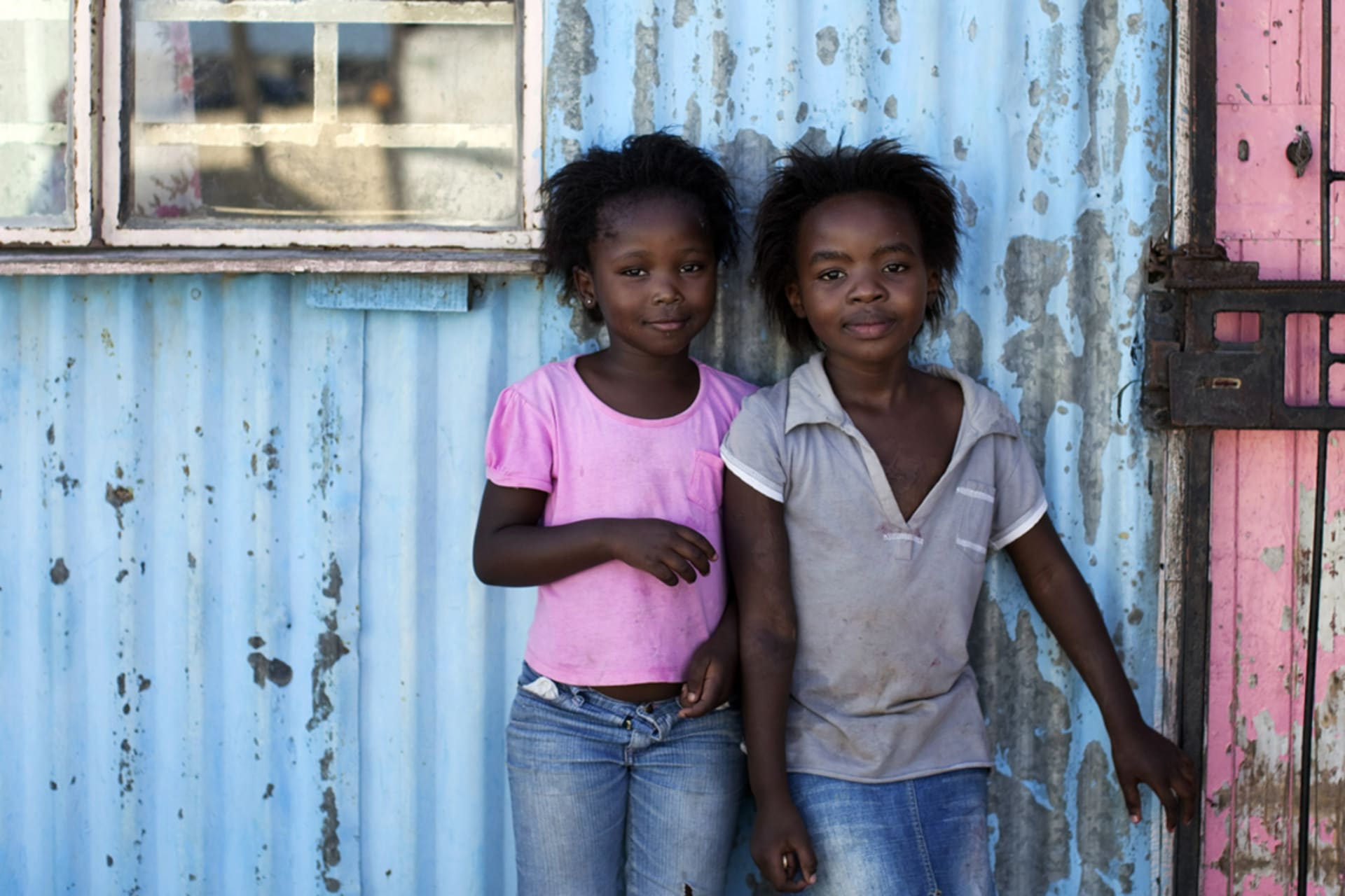 <p>Girls stand outside shacks made from metal in Cape Town’s Khayelitsha township.</p>