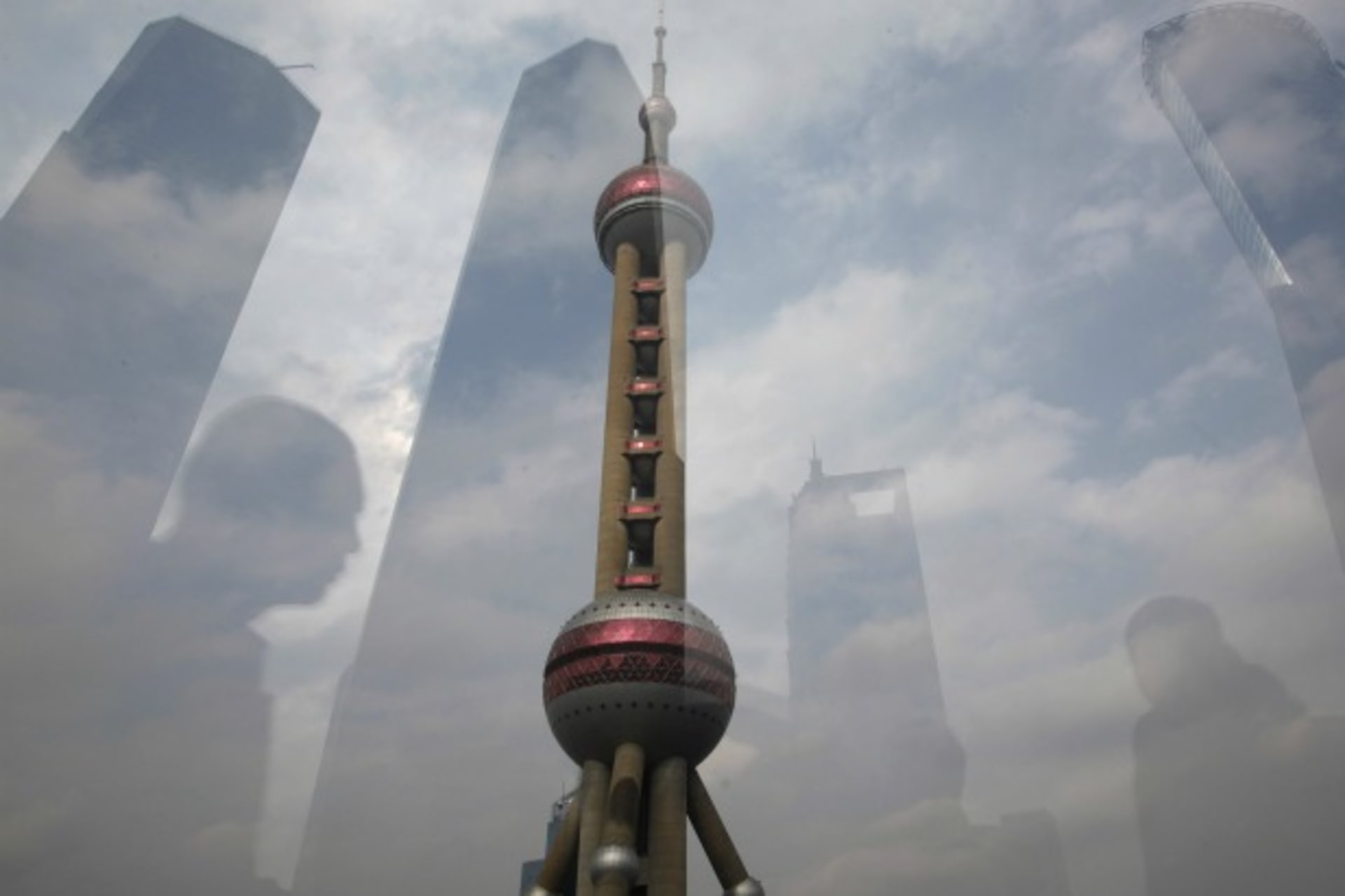 The Oriental Pearl Tower is pictured through a glass wall as people walking past and the skyline behind are reflected on the wall in the financial district of Pudong. (Aly Song / Courtesy Reuters)