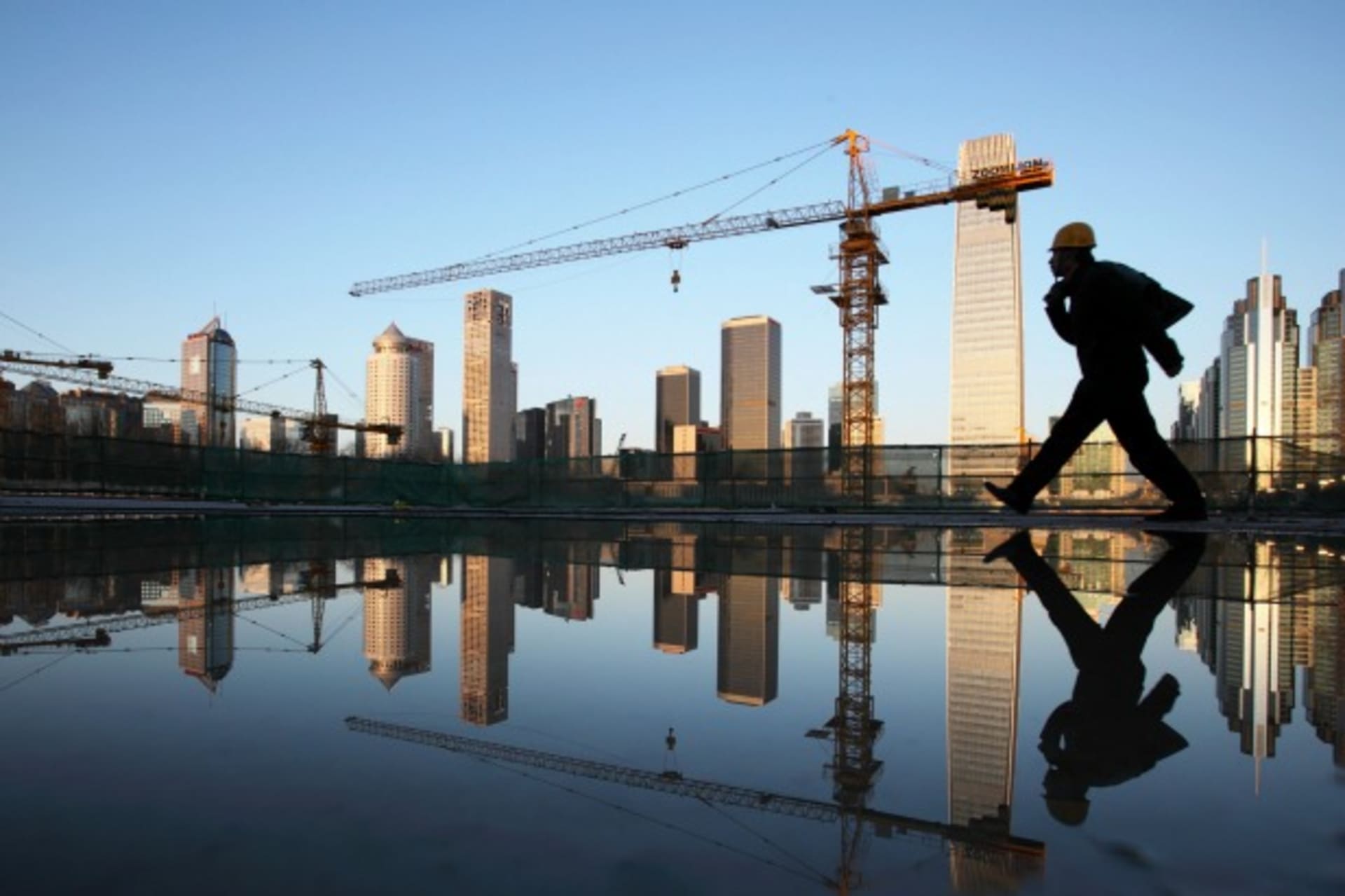 <p>A worker walks past a pool of water inside a construction site in central Beijing on April 6, 2013.</p>
