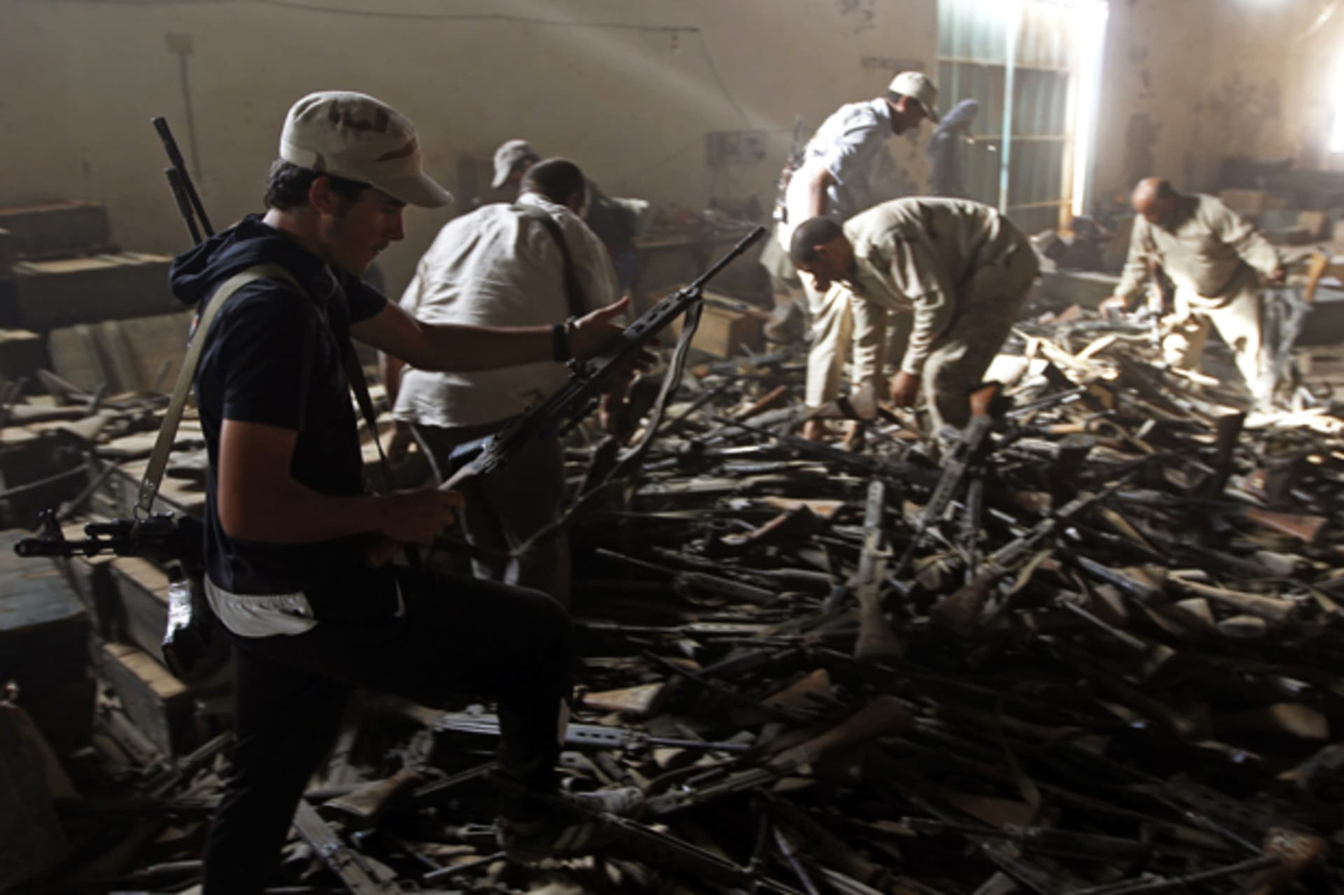 Anti-Gaddafi fighters salvage weapons from a pro-Gaddafi loyalist weapons and ammunition compound in a village near Sirte