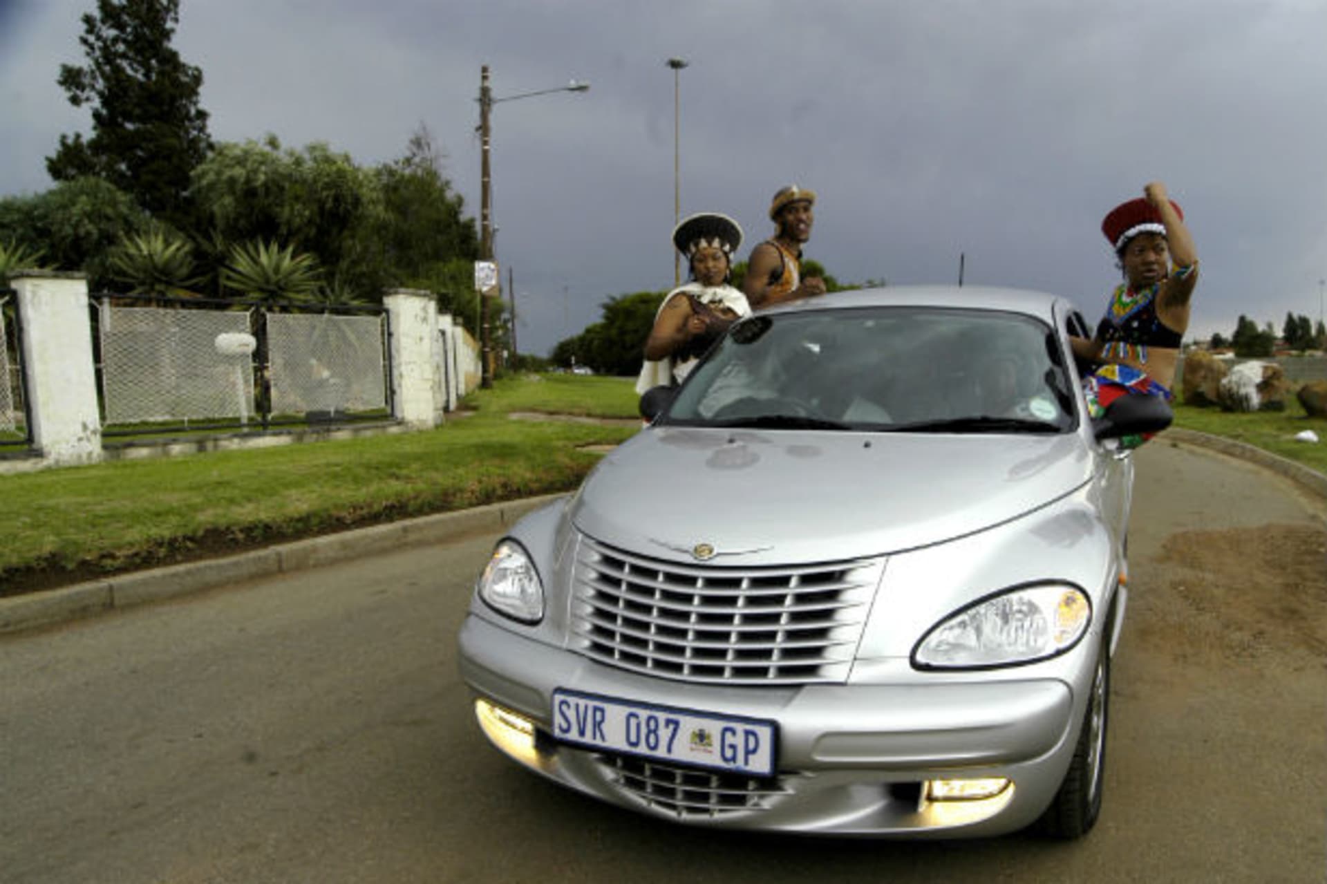 Township residents pose on a luxury car in Soweto's Thokoza Park March 25, 2006.