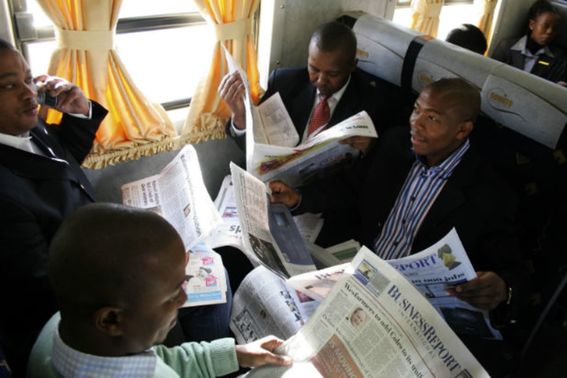 Passengers read newspapers on a business express train in Johannesburg December 11, 2008.