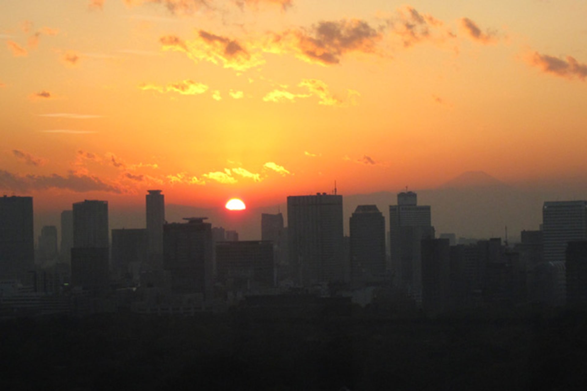 <p>Buildings are silhouetted against the setting sun in front of Mount Fuji in Tokyo</p>
