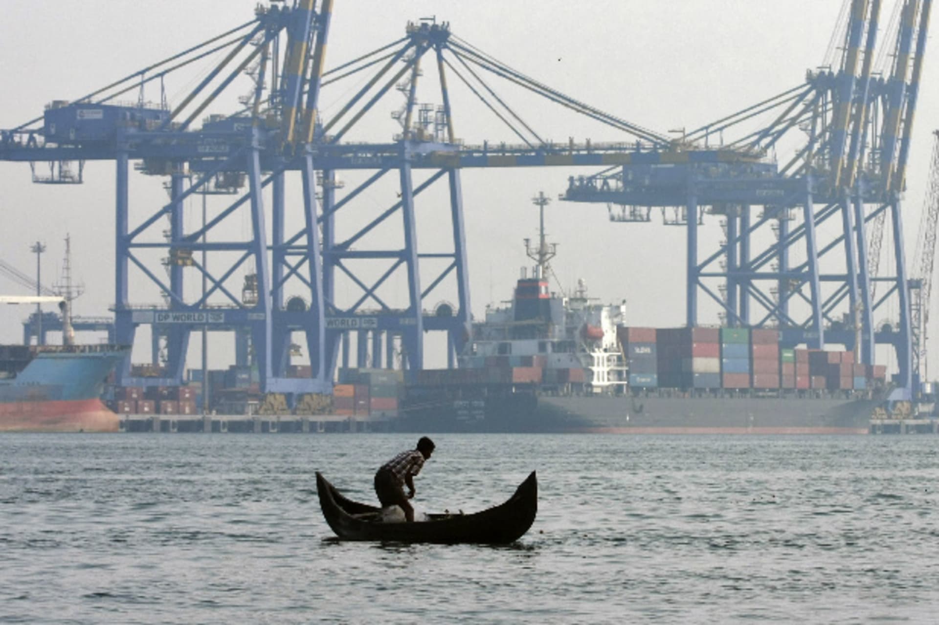 <p>A fisherman prepares to cast his fishing net in the waters of the Vembanad lake as a container ship is seen docked in the background at a port in Vallarpadam, in the southern Indian city of Kochi on February 11, 2014 (Sivaram V/Courtesy: Reuters).</p>
