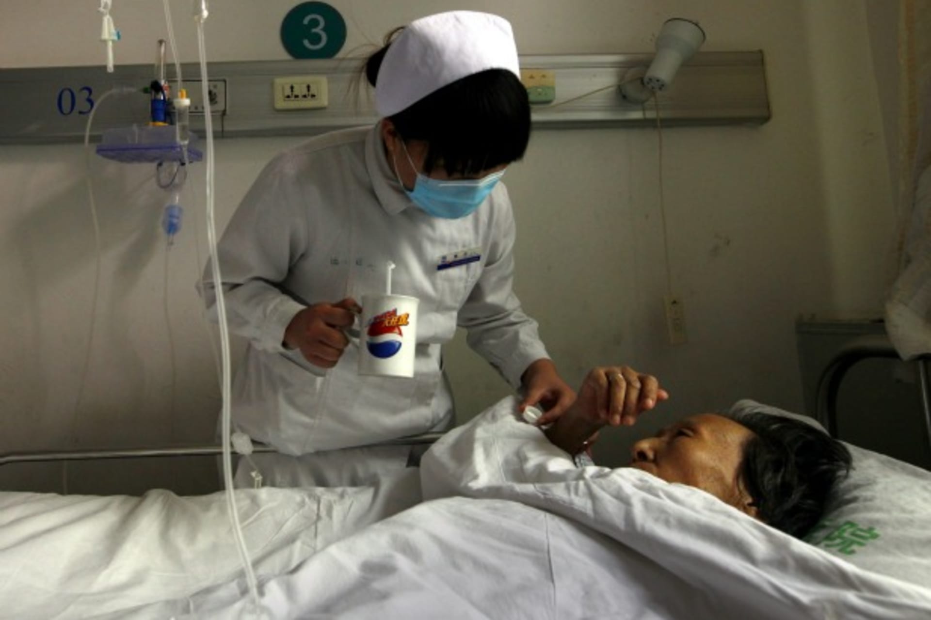 <p>A nurse gives an infected patient medicine as she lies in her bed at the HIV/AIDS ward of Beijing YouAn Hospital on December 1, 2011.</p>
