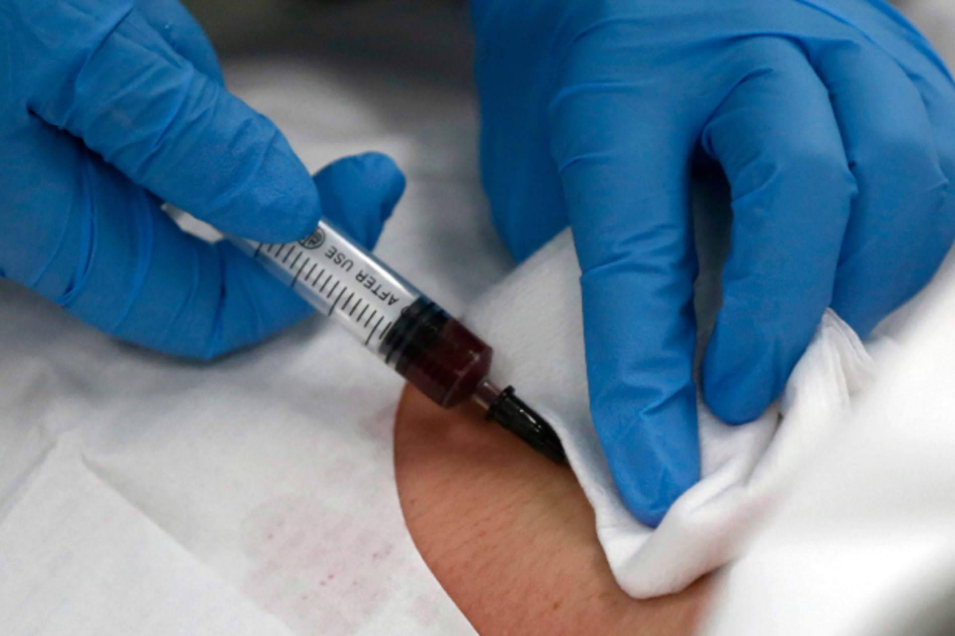 A doctor draws blood from the neck of a patient at an emergency room of a hospital in Shanghai May 15, 2013.