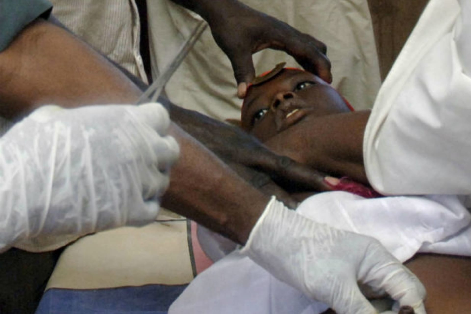 Fathers surround a boy as a doctor performs surgery during an Islamic group's circumcision session for boys in Khartoum April 7, 2012.