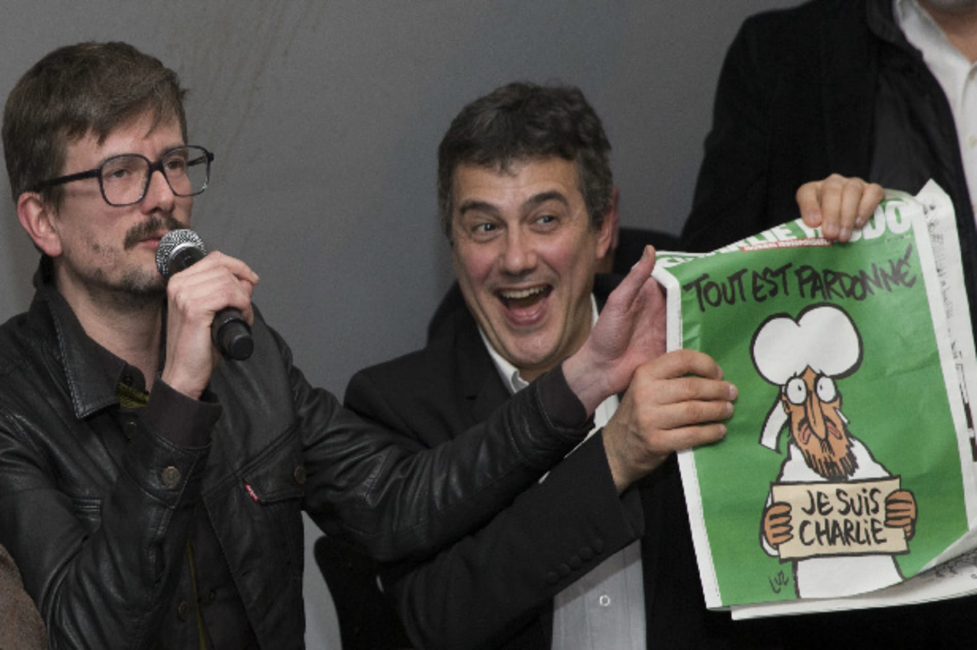 Satirical French magazine Charlie Hebdo columnist Patrick Pelloux (R) and cartoonist Luz (L) show a copy of their next issue titled "Tout est pardonne" ("All is forgiven") showing a caricature of Prophet Mohammad during a news conference at the