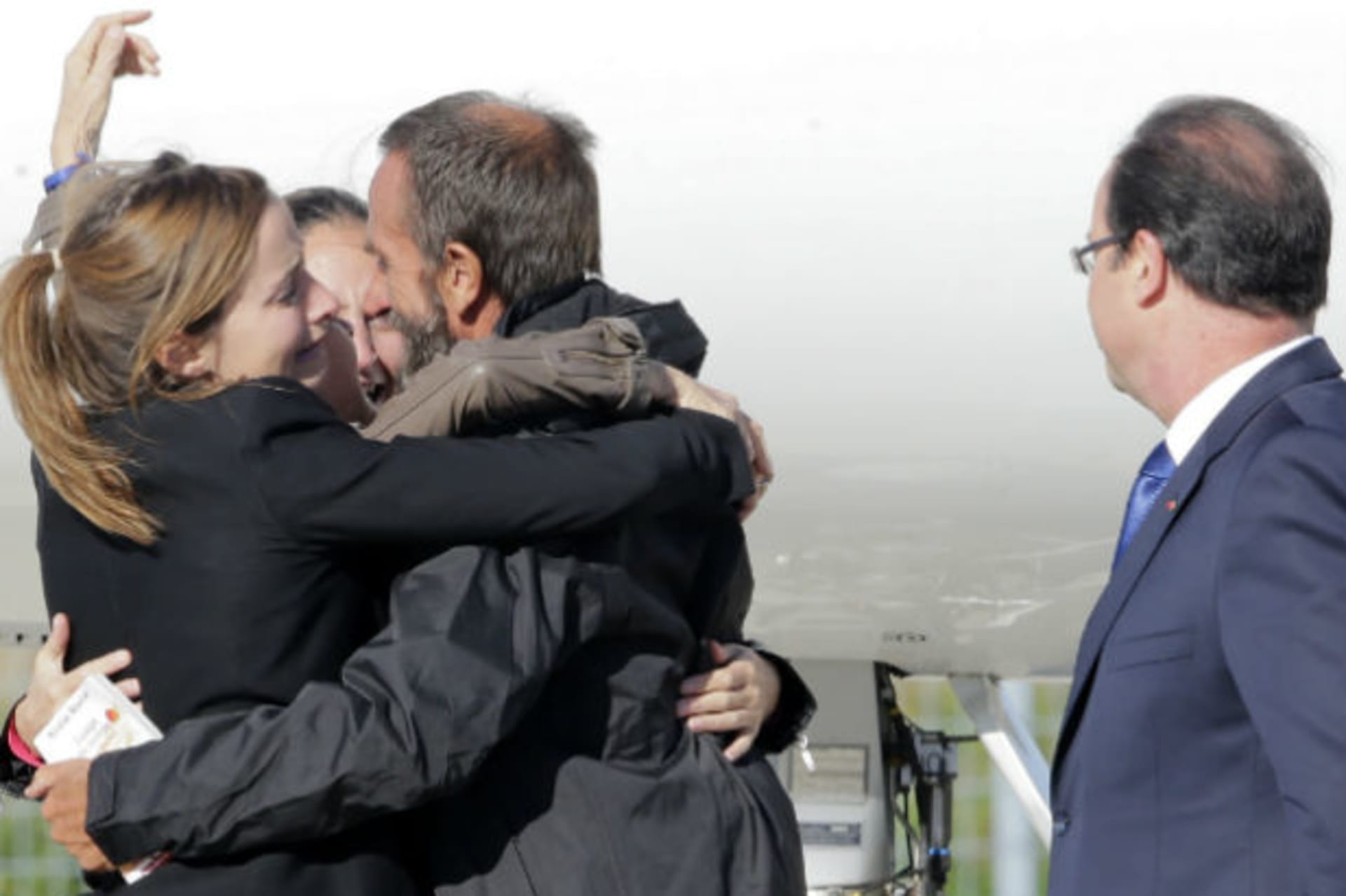 Former French hostage Daniel Larribe is welcomed by relatives as French President Francois Hollande looks on on the tarmac upon their arrival at Villacoublay military airport, near Paris, October 30, 2013 (Jacky Naegelen/Courtesy Reuters).