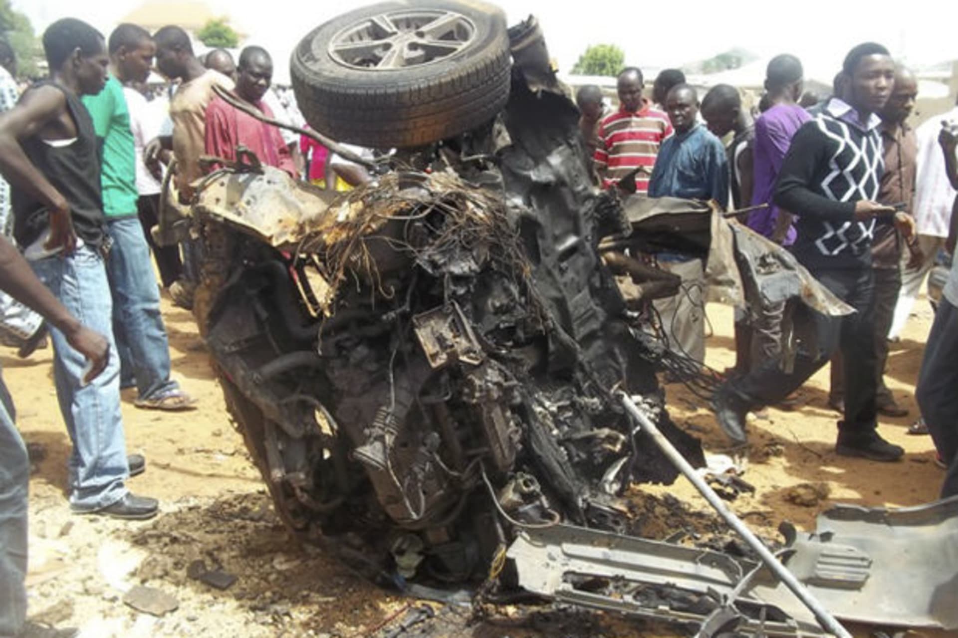 People stand by the wreckage from a car bomb explosion at a church in Yelwa on the outskirts of the northern Nigerian city of Bauchi, June 3, 2012.