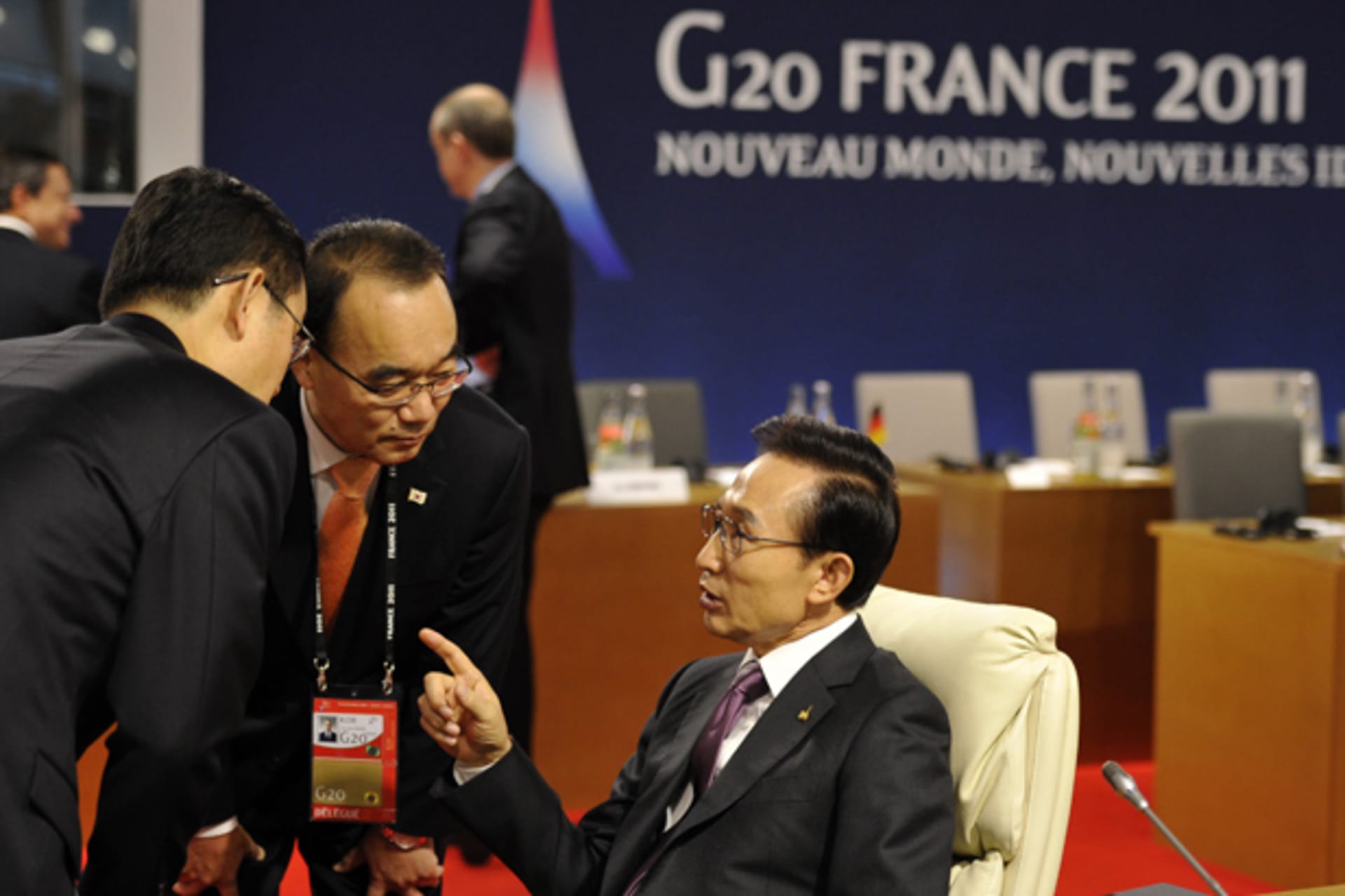 South Korea's President Lee Myung-bak speaks to members of his delegation while awaiting the start of a meeting on the second day of the G20 Summit in Cannes