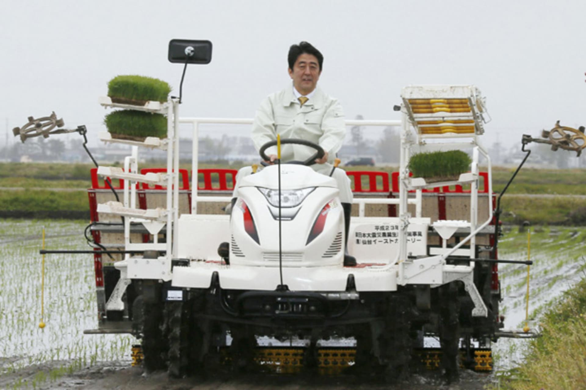 Japan's Prime Minister Shinzo Abe drives a rice planting machine at a a paddy field in Sendai
