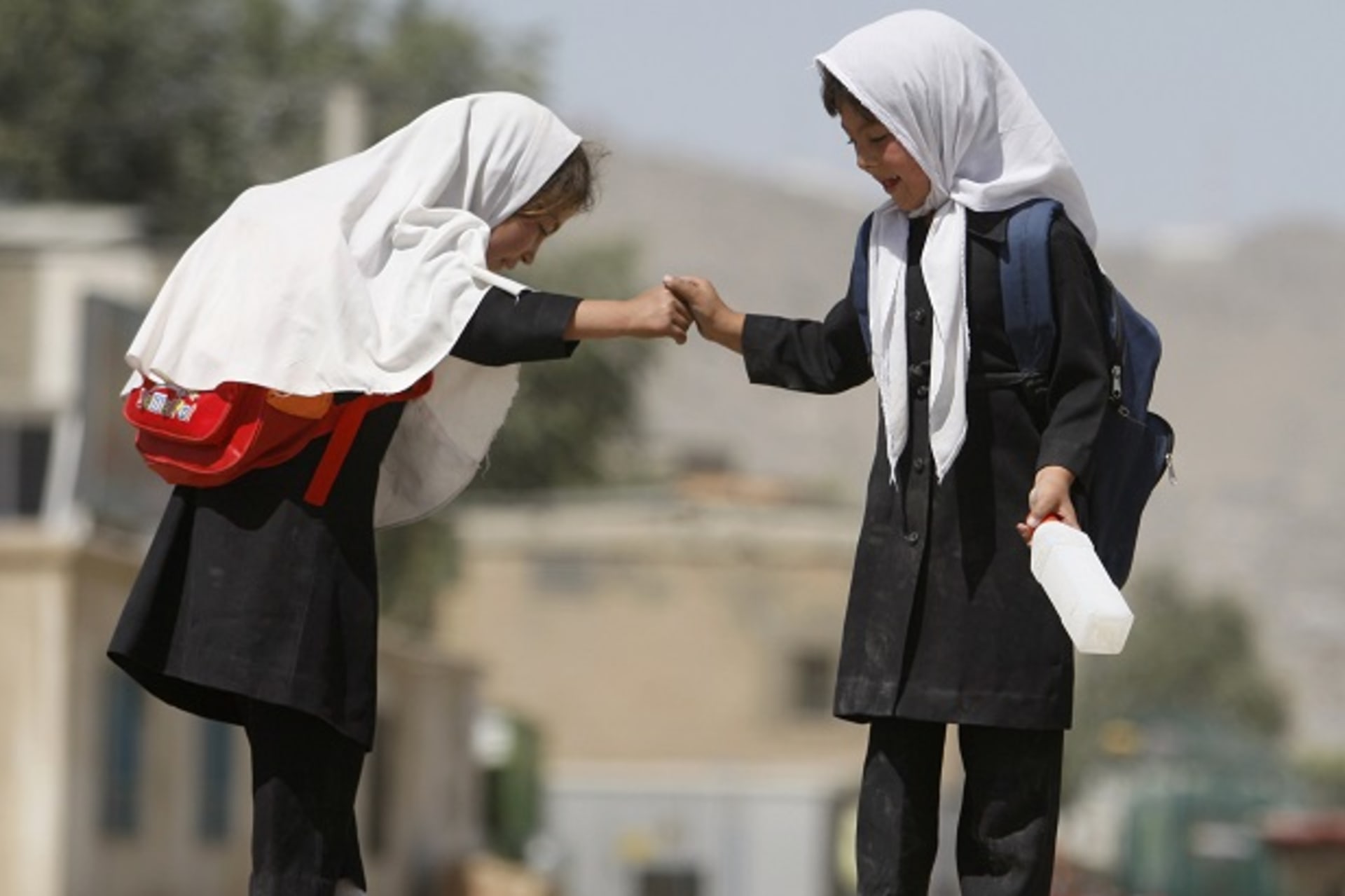 Schoolgirls balance on a wall in Kabul