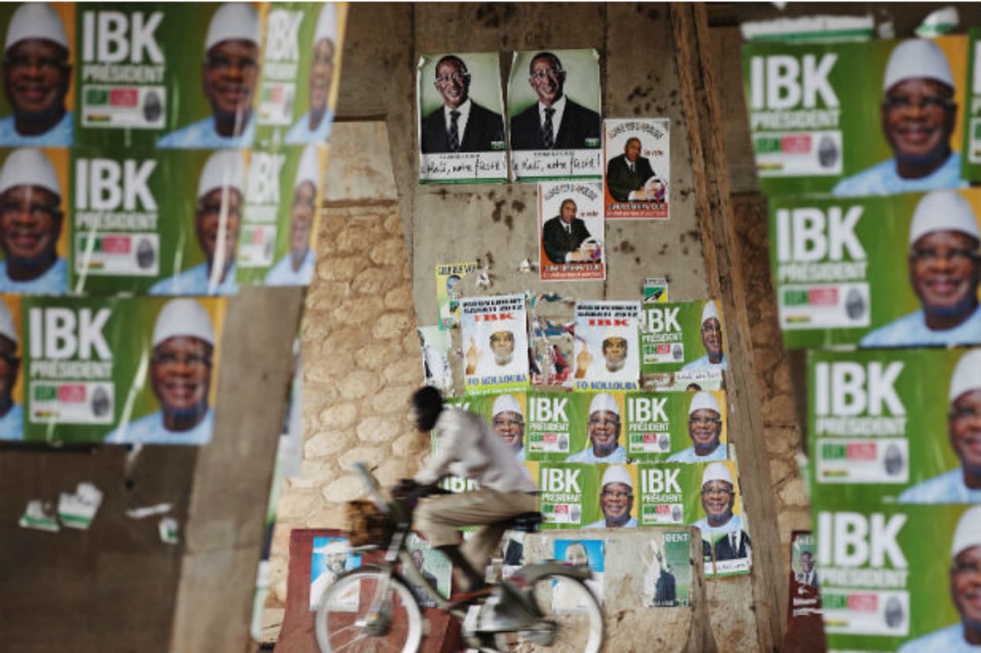 A man rides a bicycle past electoral campaign posters in Bamako August 9, 2013.