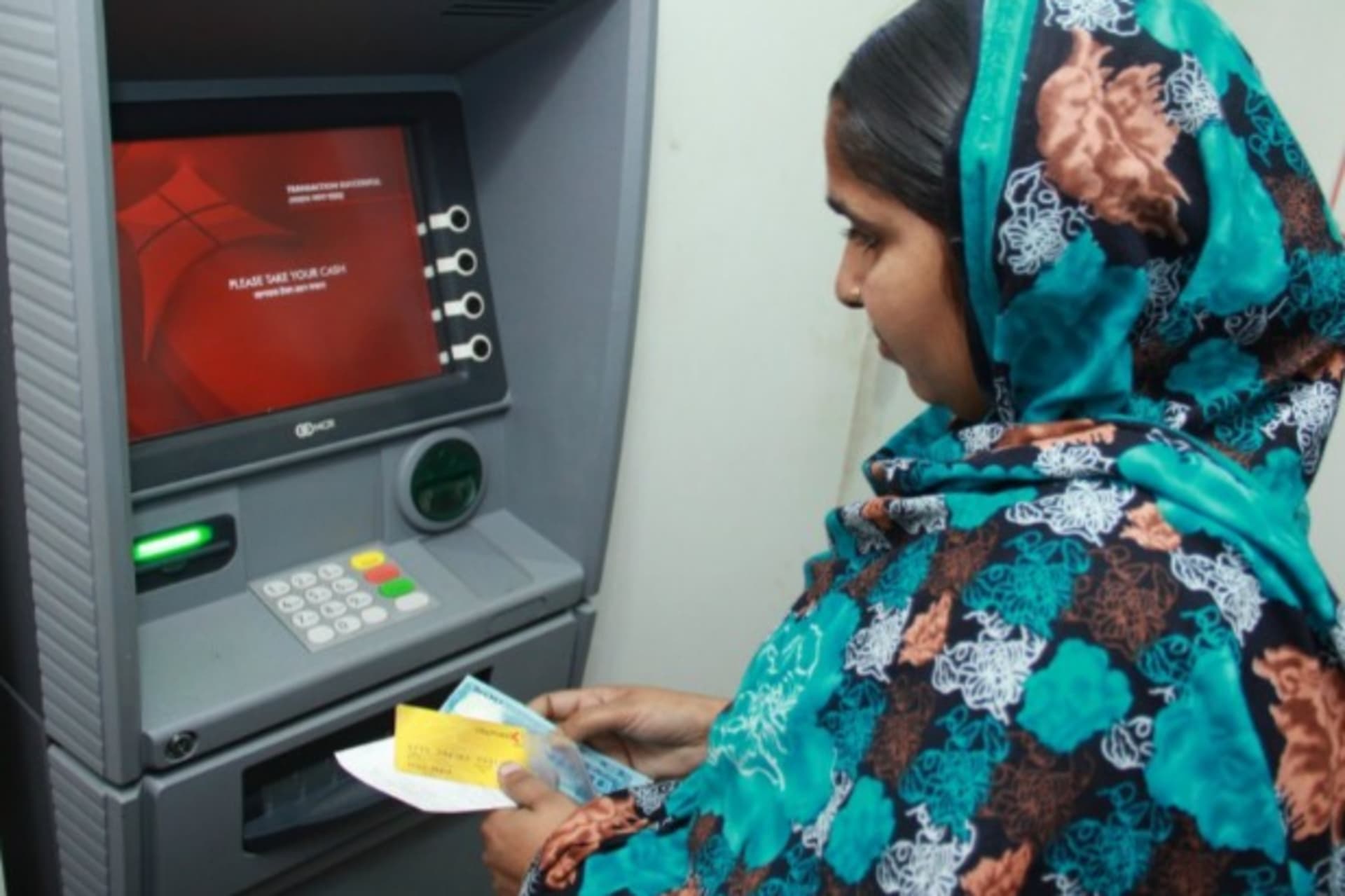 <p>A worker uses an ATM newly installed in her factory in Dhaka, Bangladesh, June 2014 (Courtesy Camilla Fabbri/World Bank).</p>