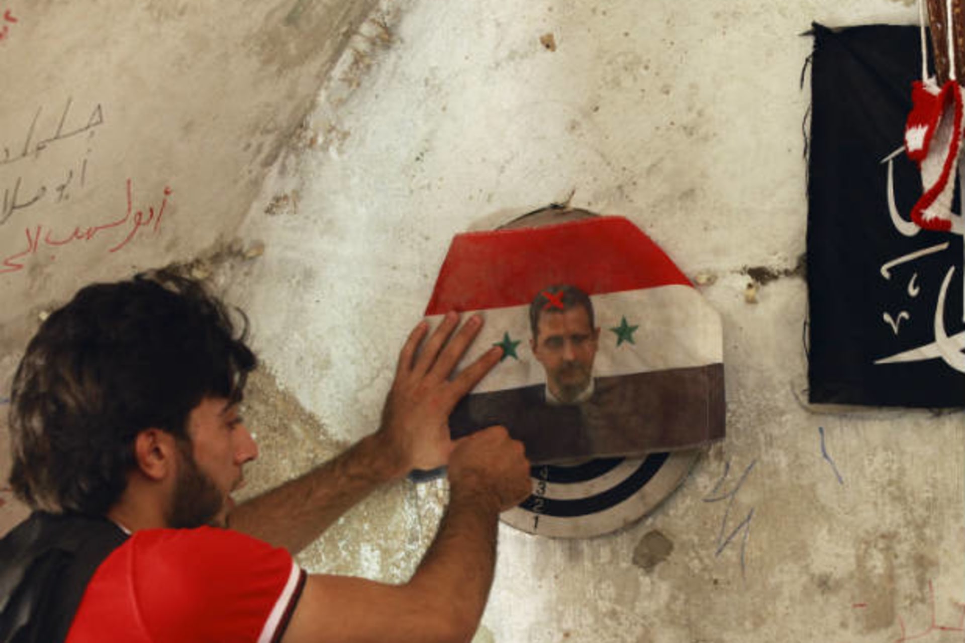 A member of the Free Syrian Army plays darts on a picture of Syrian President Bashar al-Assad in the Bab al-Nasr neighborhood of Aleppo June 28, 2013 (Khatib/Courtesy Reuters).