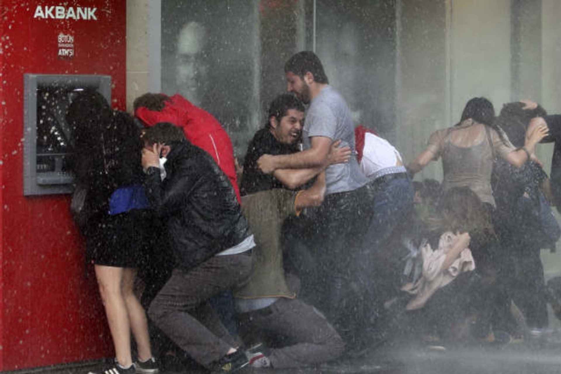 Anti-government protesters try to protect themselves from a water cannon as riot police disperse them during a protest in Ankara June 5, 2013 (Bektas/Courtesy Reuters)..