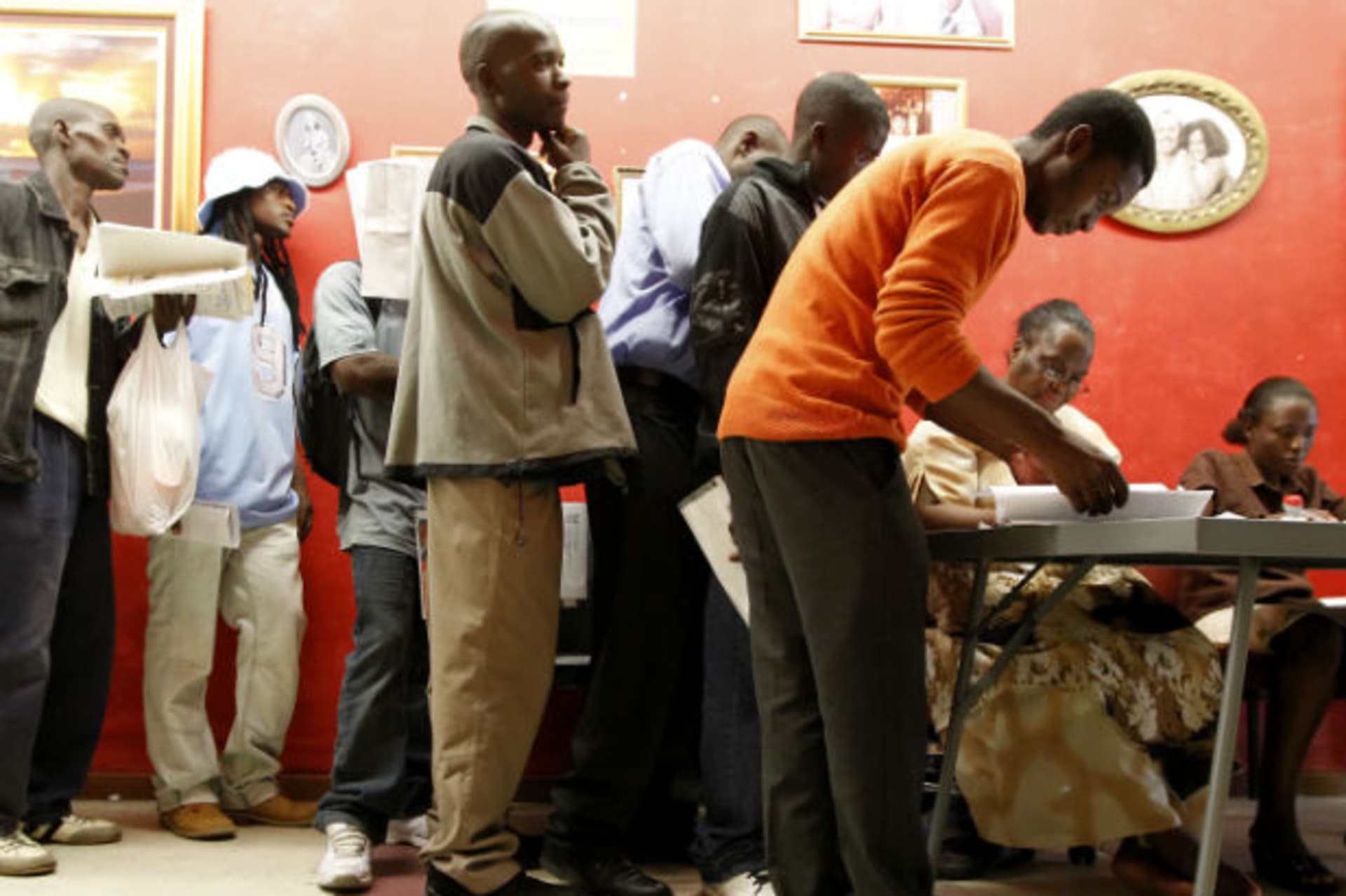 Zimbabweans recieve forms as they queue to apply for residence and study permits outside the Home Affairs office in Cape Town, December 31, 2010.