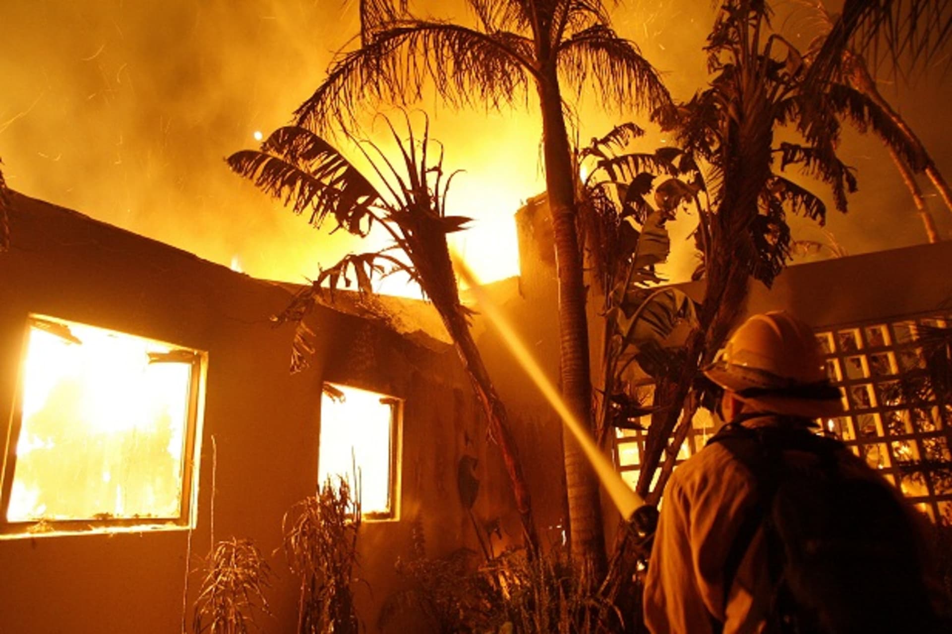 <p>A firefighter sprays water on a burning house in Santa Barbara, California (Mario Anzuoni/Courtesy Reuters).</p>
