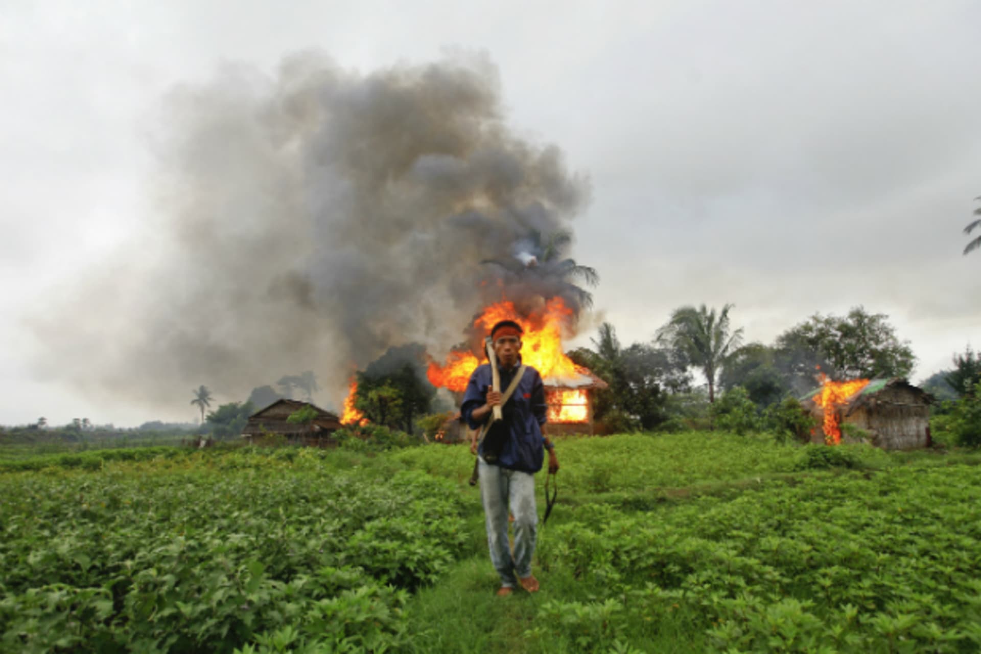 <p>An ethnic Rakhine man holds homemade weapons as he walks in front of houses that were burnt during fighting between Buddhist Rakhine and Muslim Rohingya communities in Sittwe on June 10, 2012. (Courtesy Reuters)</p>
