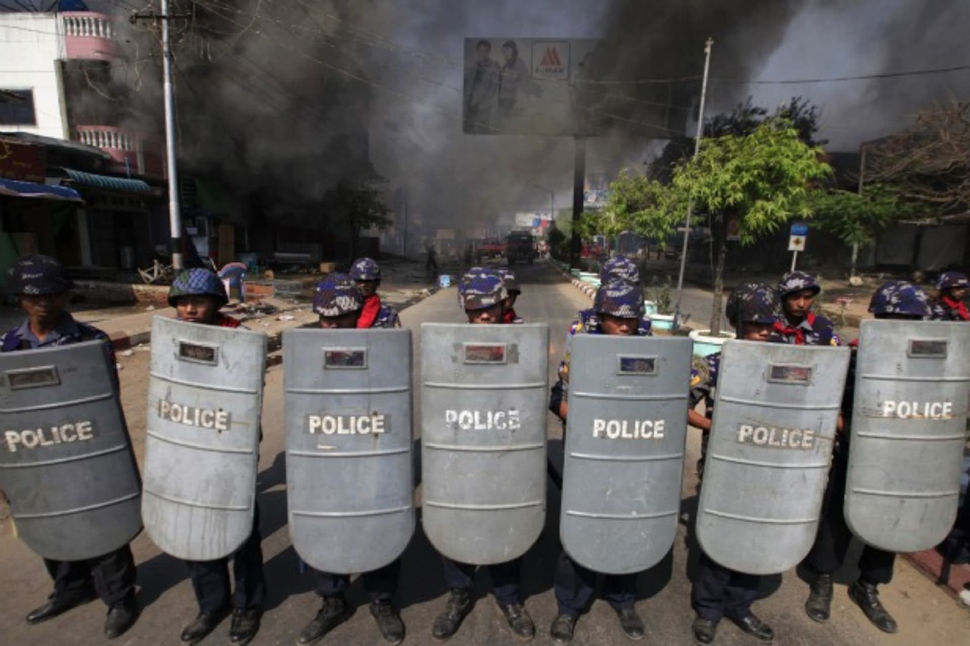 <p>Riot policemen form up near a fire during riots in Meikhtila on March 22, 2013.</p>
