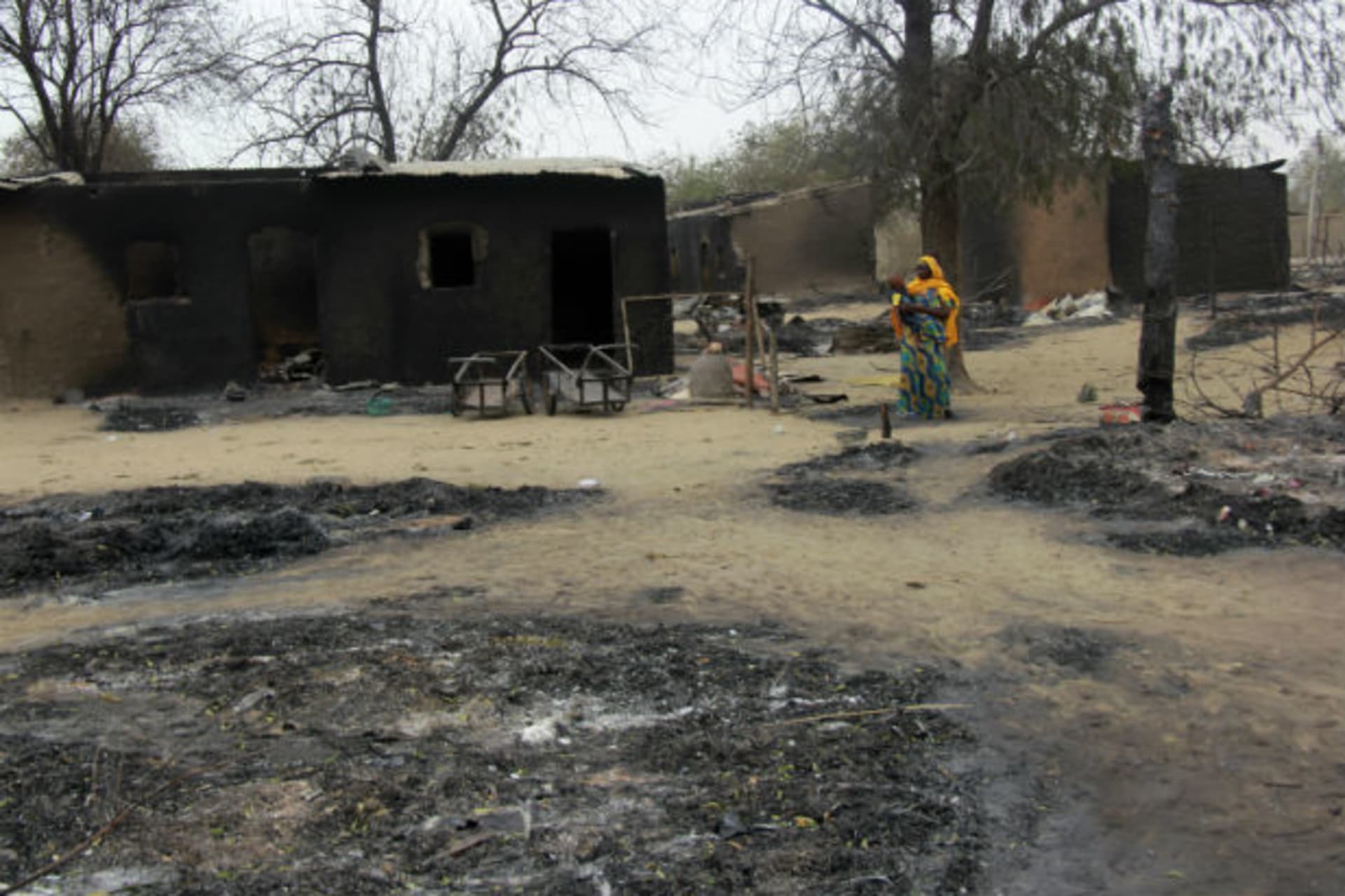 A woman carrying a child stands near burnt houses in the aftermath of what Nigerian authorities said was heavy fighting between security forces and Islamist militants in Baga, a fishing town on the shores of Lake Chad, adjacent to the Chadian b