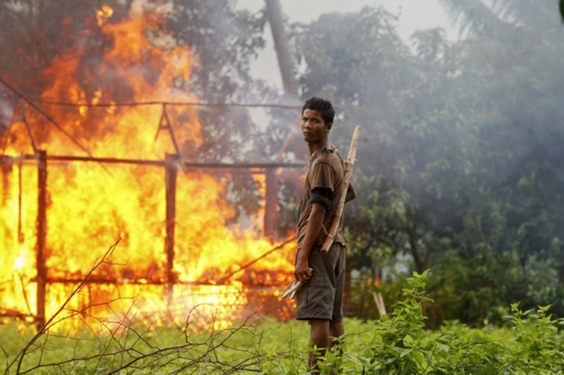 <p>An ethnic Rakhine man holds homemade weapons as he stands in front of a house that was burnt during fighting between Buddhist Rakhine and Muslim Rohingya communities in Sittwe.</p>
