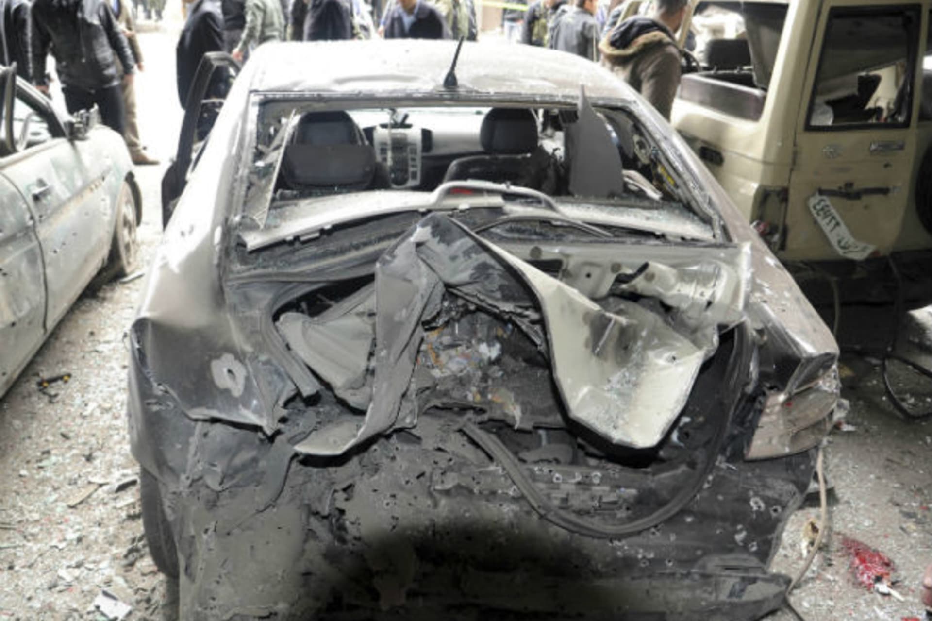 People gather around damaged cars at the site of an explosion in the Maidan district of Damascus January 6, 2012, in this handout photograph released by Syria's national news agency SANA. A suicide bomber killed several people and wounded dozen