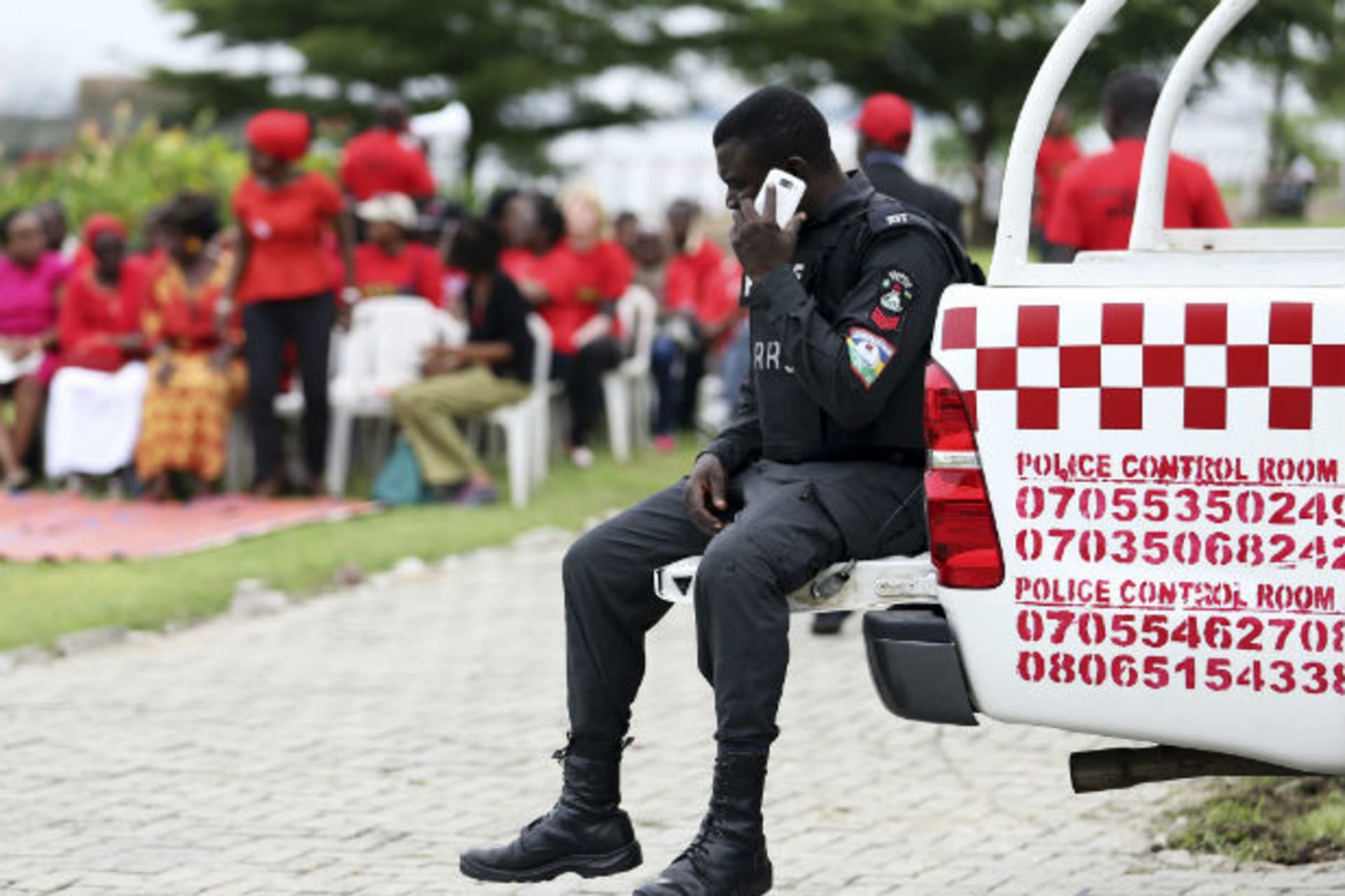 A policeman sitting at the back of a truck makes a phone call before the start of a speak-out session of 'bring back our girls' rally in Lagos June 7, 2014.
