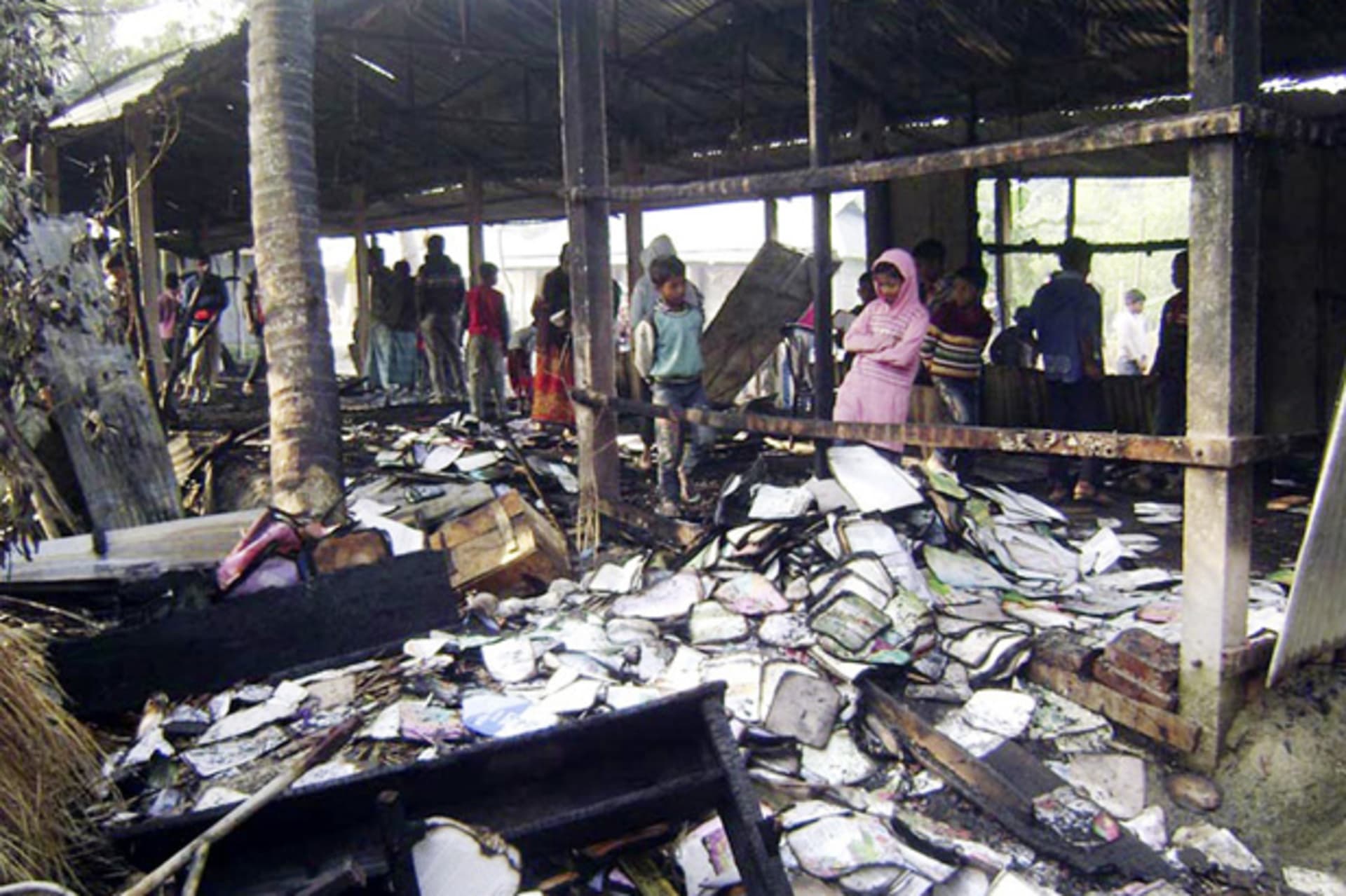 <p>People look at burnt textbooks after a primary school which was supposed to be used as a polling booth was set on fire, in Feni January 4, 2014 (Courtesy Reuters).</p>

