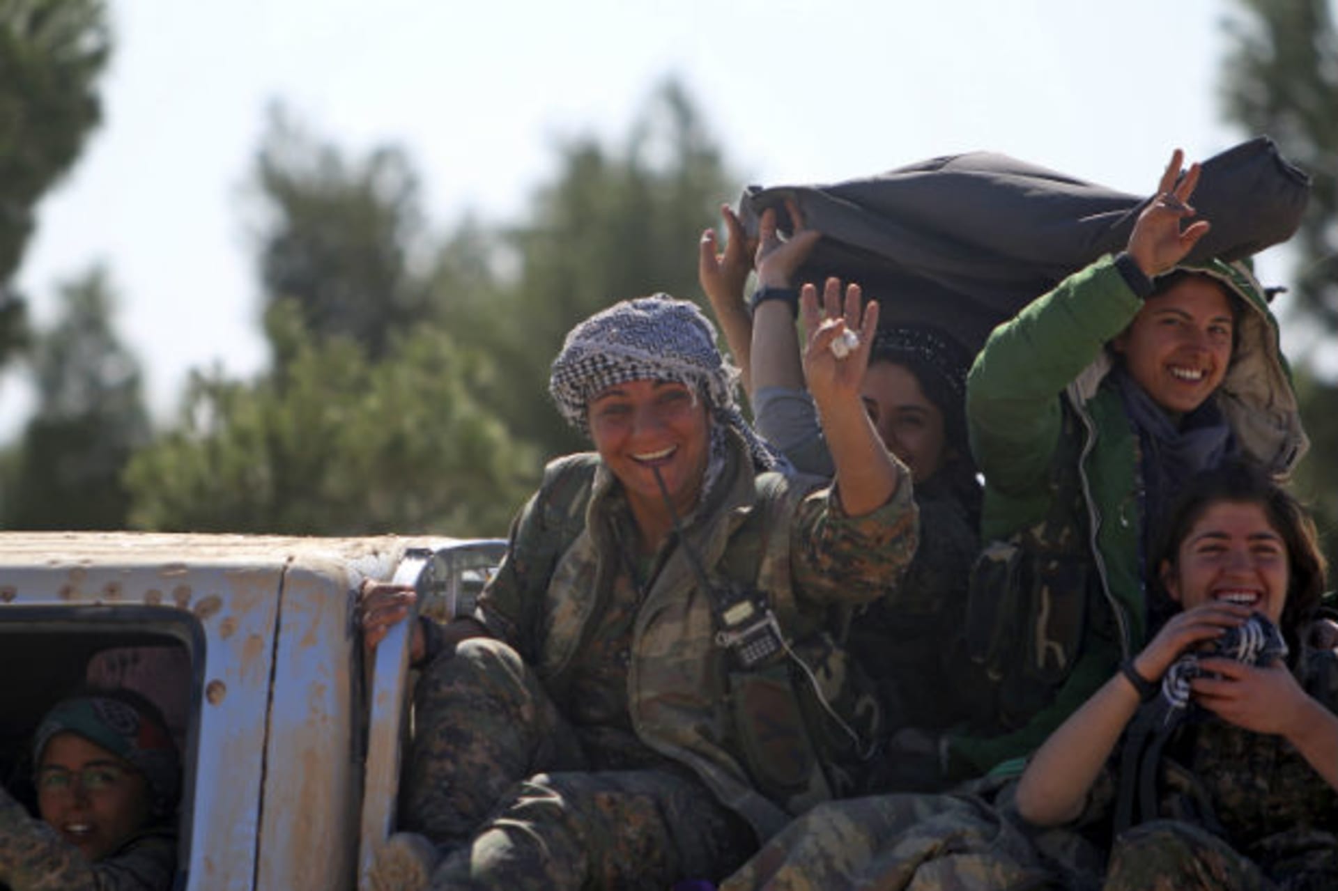 <p>Democratic Forces of Syria women fighters gesture while riding a pick-up truck near the town of al-Shadadi in the Hasaka countryside of Syria on February 18, 2016.</p>
