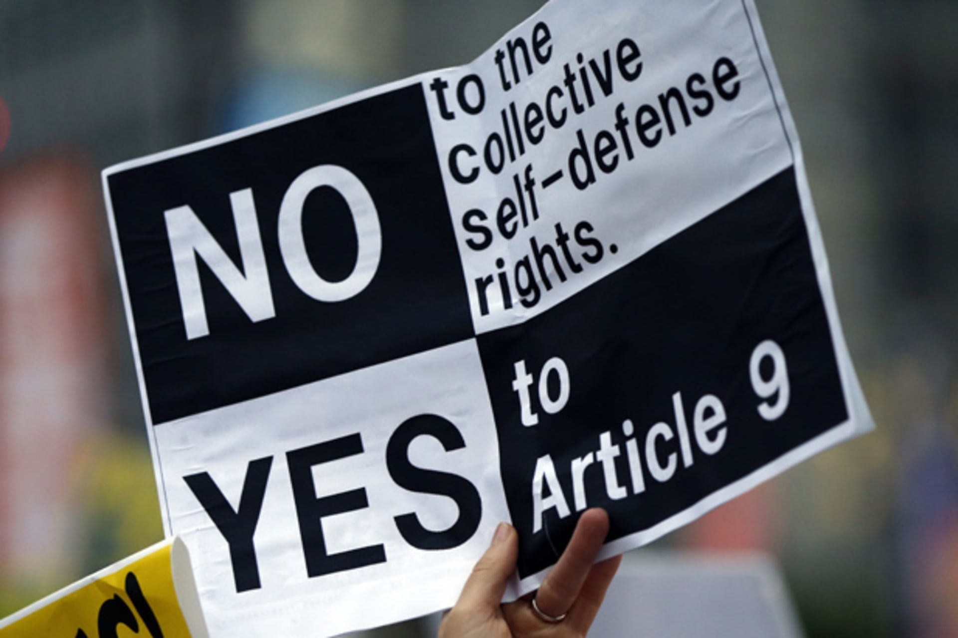 <p>A protester raises a placard as they gather at a rally against Japan’s Prime Minister Shinzo Abe’s push to expand Japan’s military role in front of Abe’s official residence in Tokyo June 30, 2014</p>