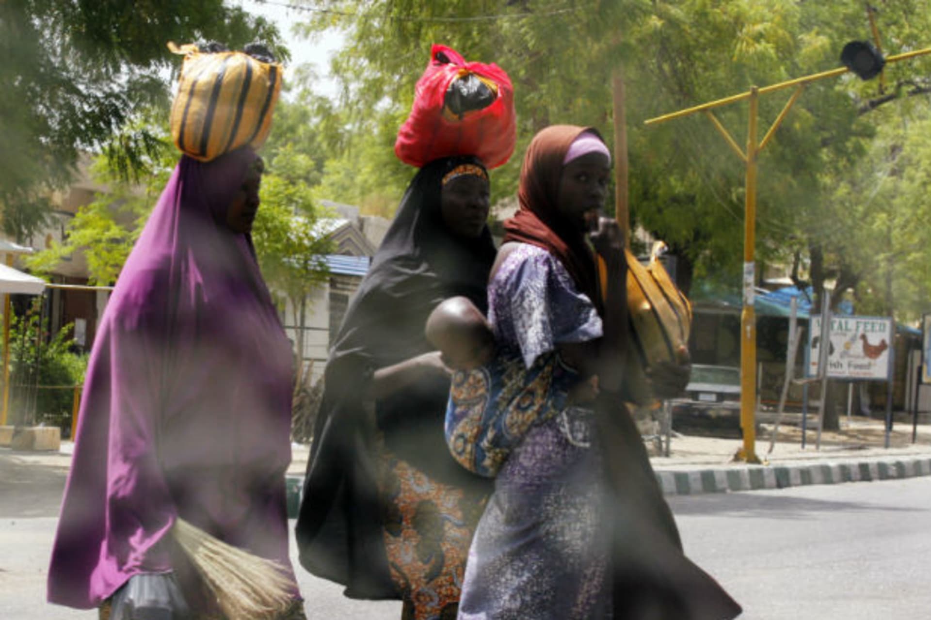 Women attempt to cross Jos Road with their belongings, after the military declared a 24-hour curfew over large parts of Maiduguri in Borno State May 19, 2013.