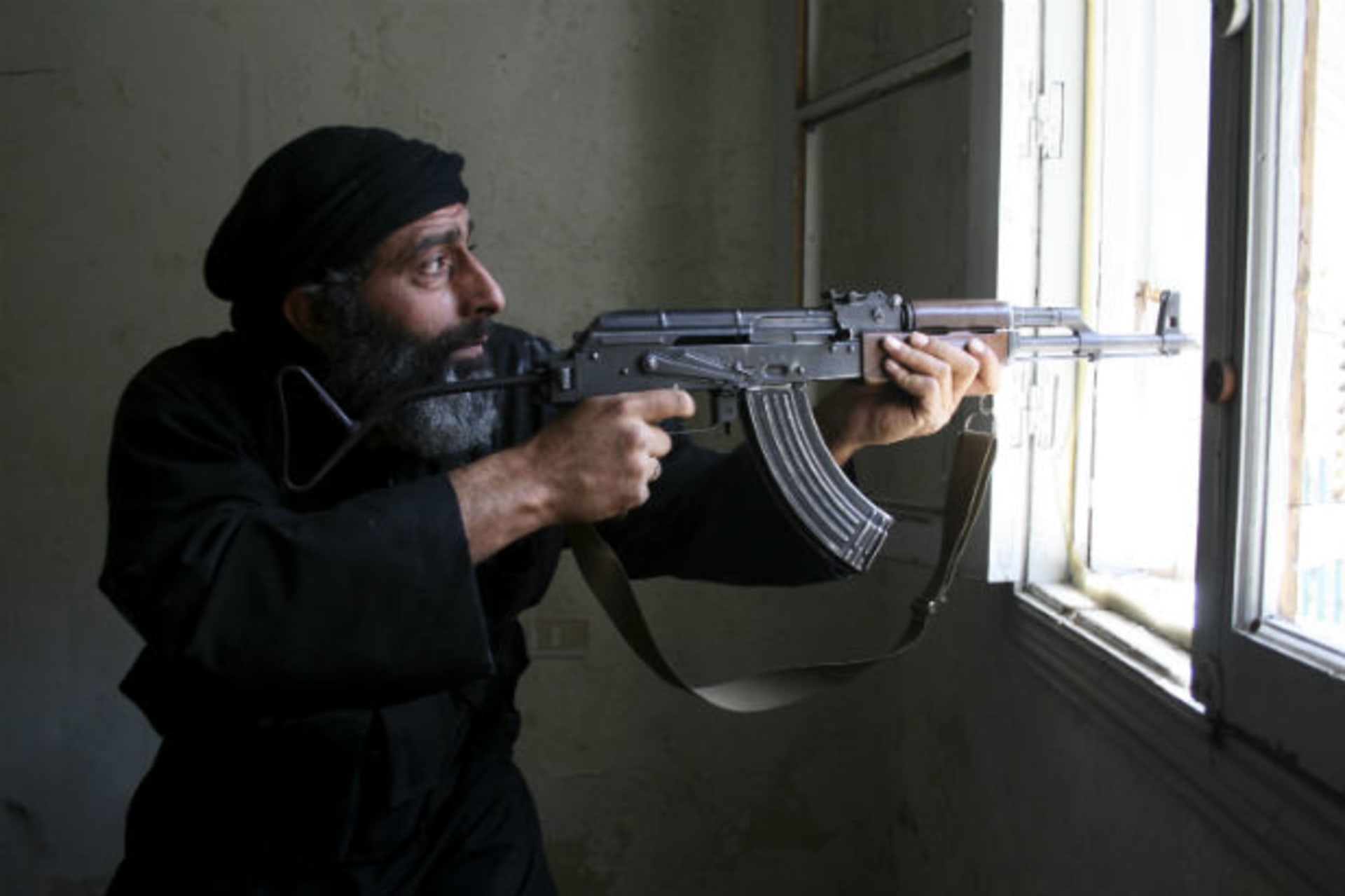 A Free Syrian Army fighter aims his AK-47 rifle through a window in Aleppo's Salaheddine neighbourhood (Hretani/Courtesy Reuters).