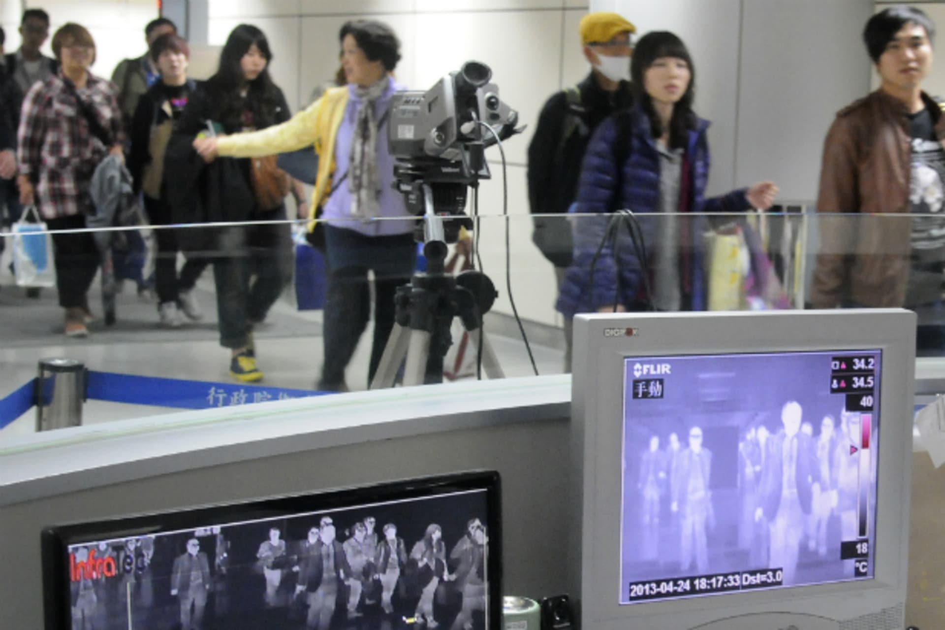 <p>Passengers walk past temperature detectors.</p>
